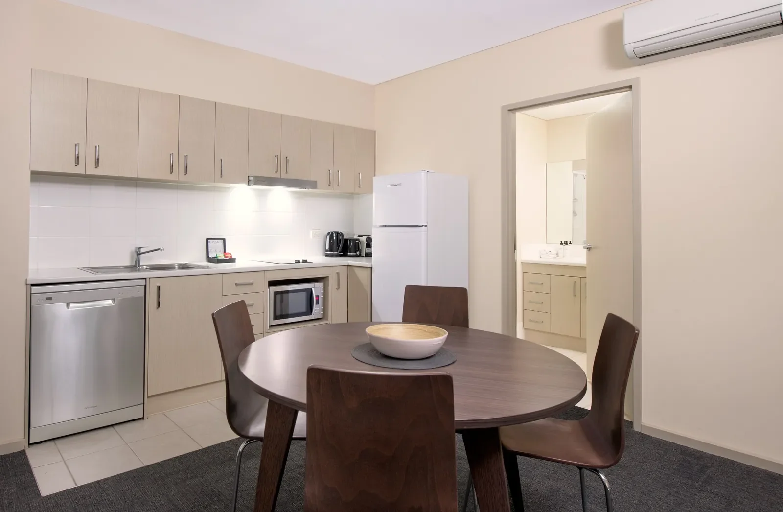 Kitchen with light wood cabinets, white appliances, and a round dining table with four chairs.