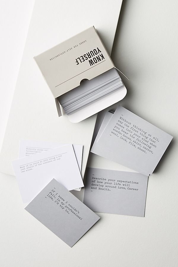 A white box labeled 'Know Yourself' containing small white cards with typed prompts, some cards are spread out on a white surface.