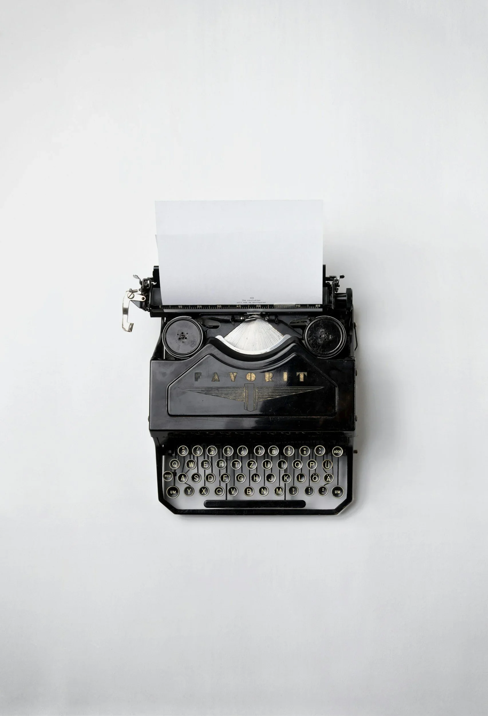 Vintage black typewriter with sheet of paper inserted, on a white background.
