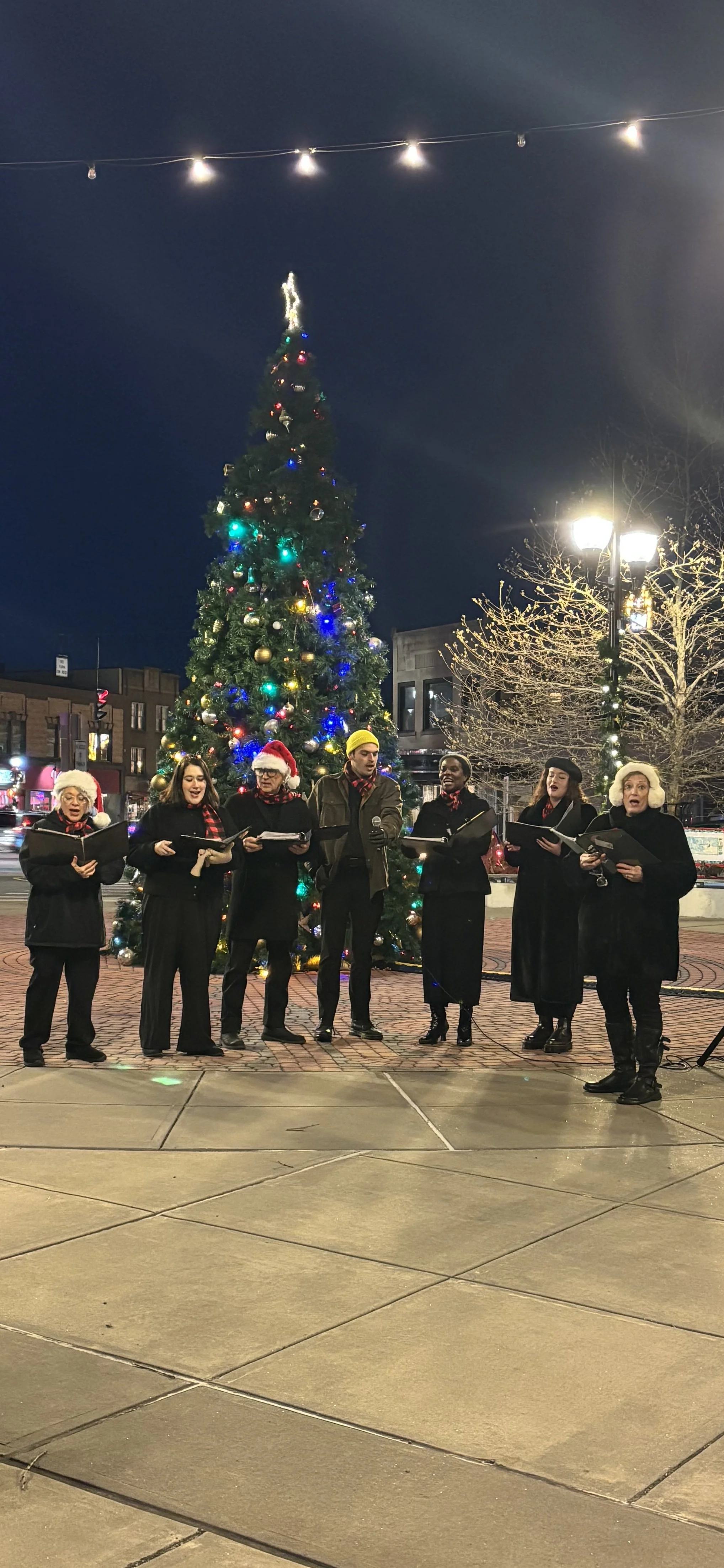 Silhouettes of three women standing in a smoky blue-lit environment, each near a microphone, on a stage likely preparing for or during a performance.
