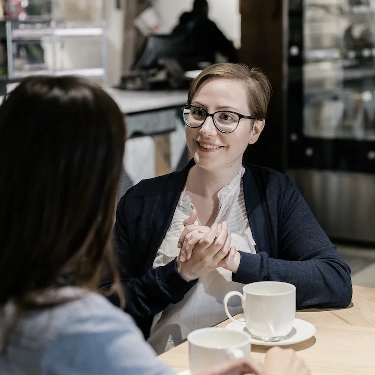 Kati Carrapa smiling across a café table with another person