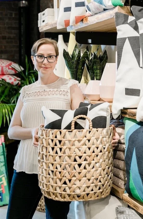 Smiling Kati Carrapa holding a large basket with pillows