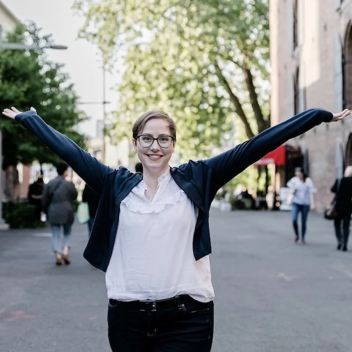 Kati Carrapa outdoors with her arms raised joyfully