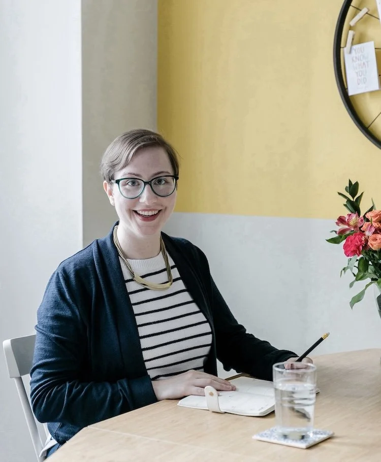 Kati Carrapa sitting at a table with a journal and pen