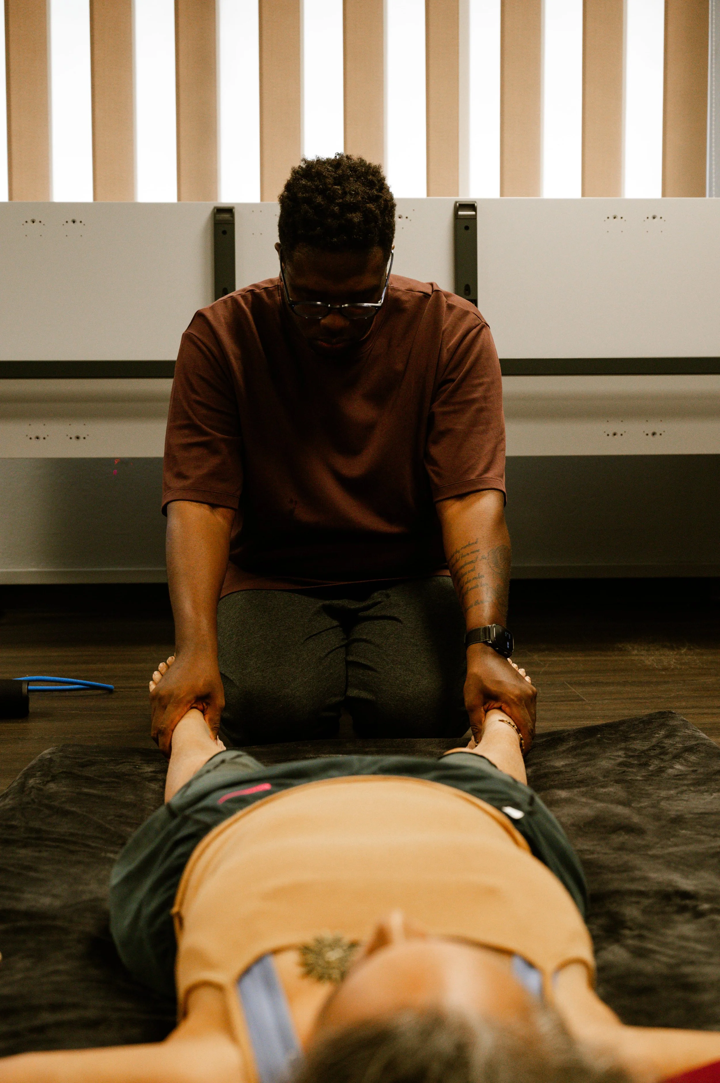 Praticien en massage thaï traditionnel travaillant les jambes d’un client allongé – Guadeloupe.