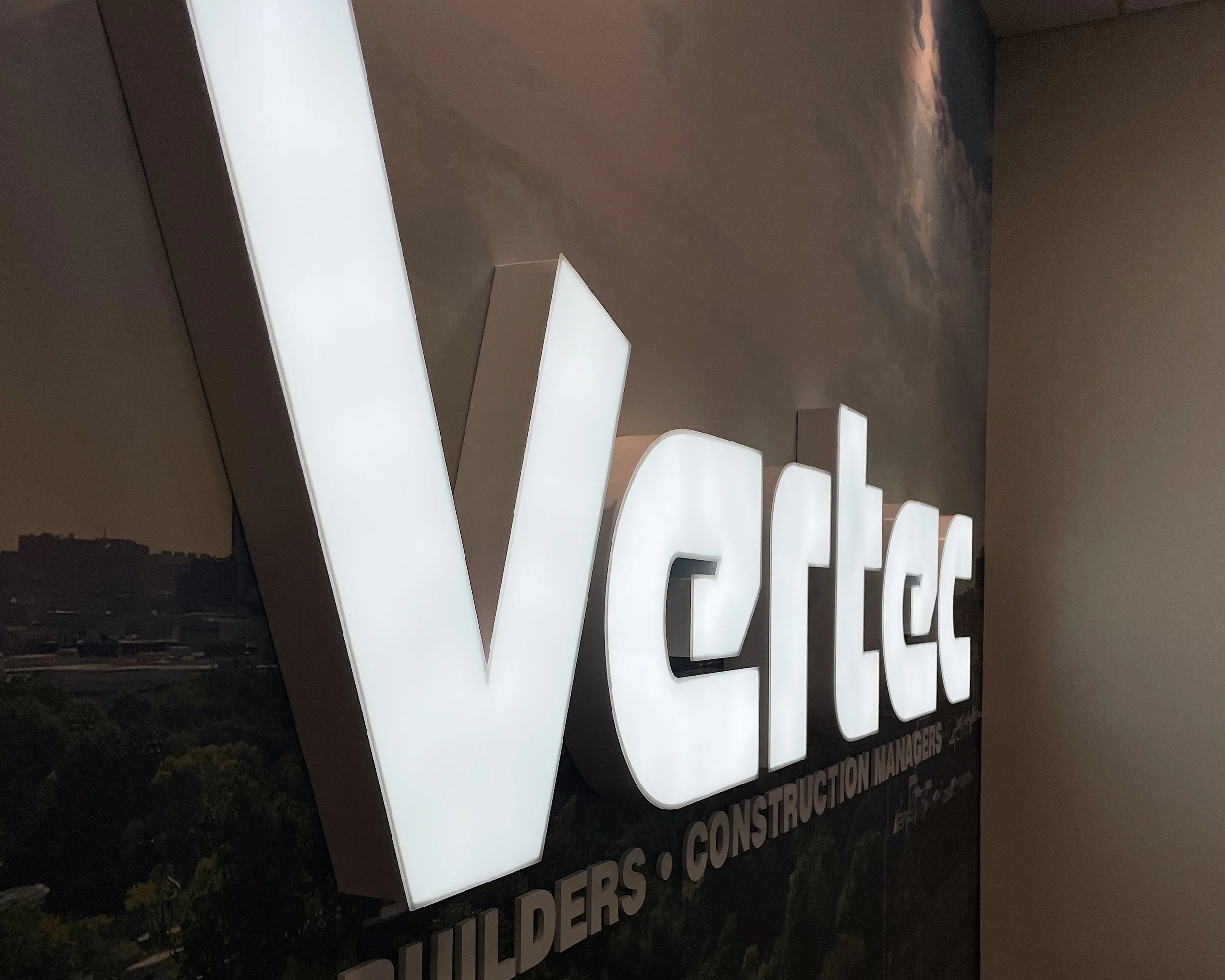 Illuminated sign reading 'Vectec' with smaller text underneath for 'Builders' and 'Construction Managers'.