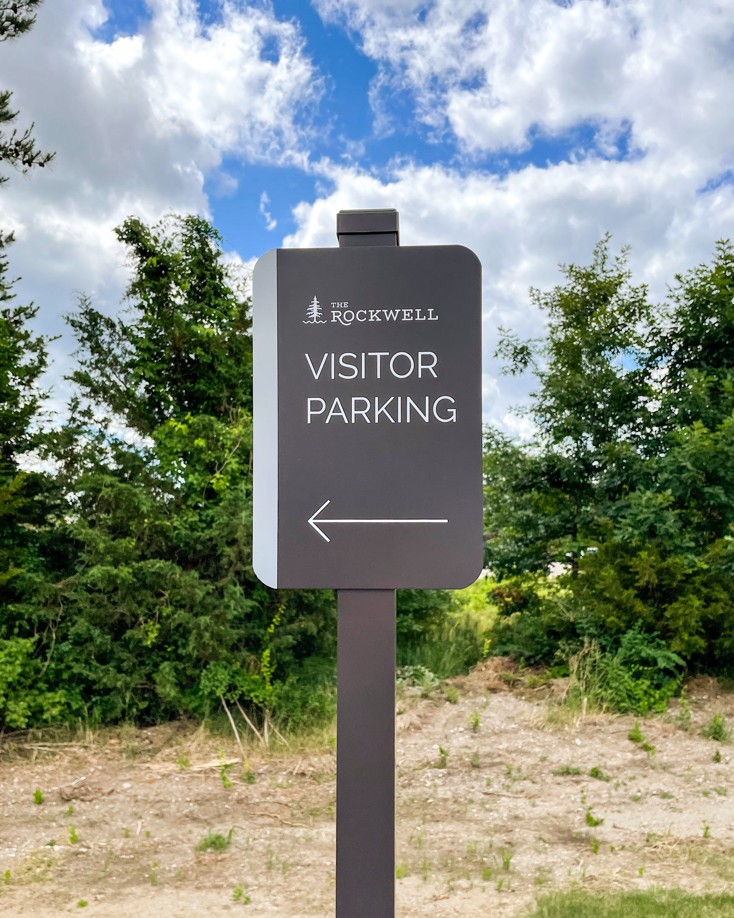 A brown sign with an arrow mounted on a post for directional instructions