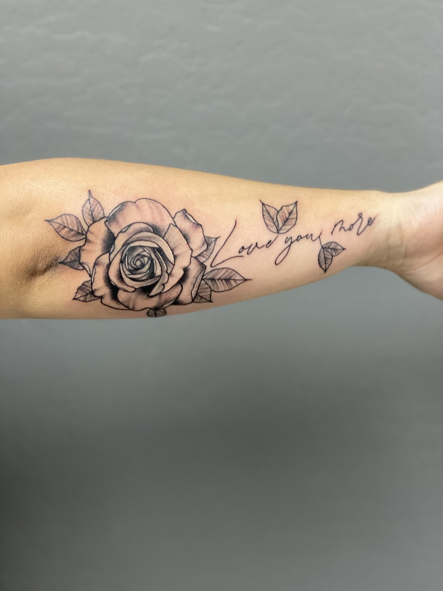 Tattoo of a with rose and leaves on an arm, with the phrase "and your move" written in cursive.