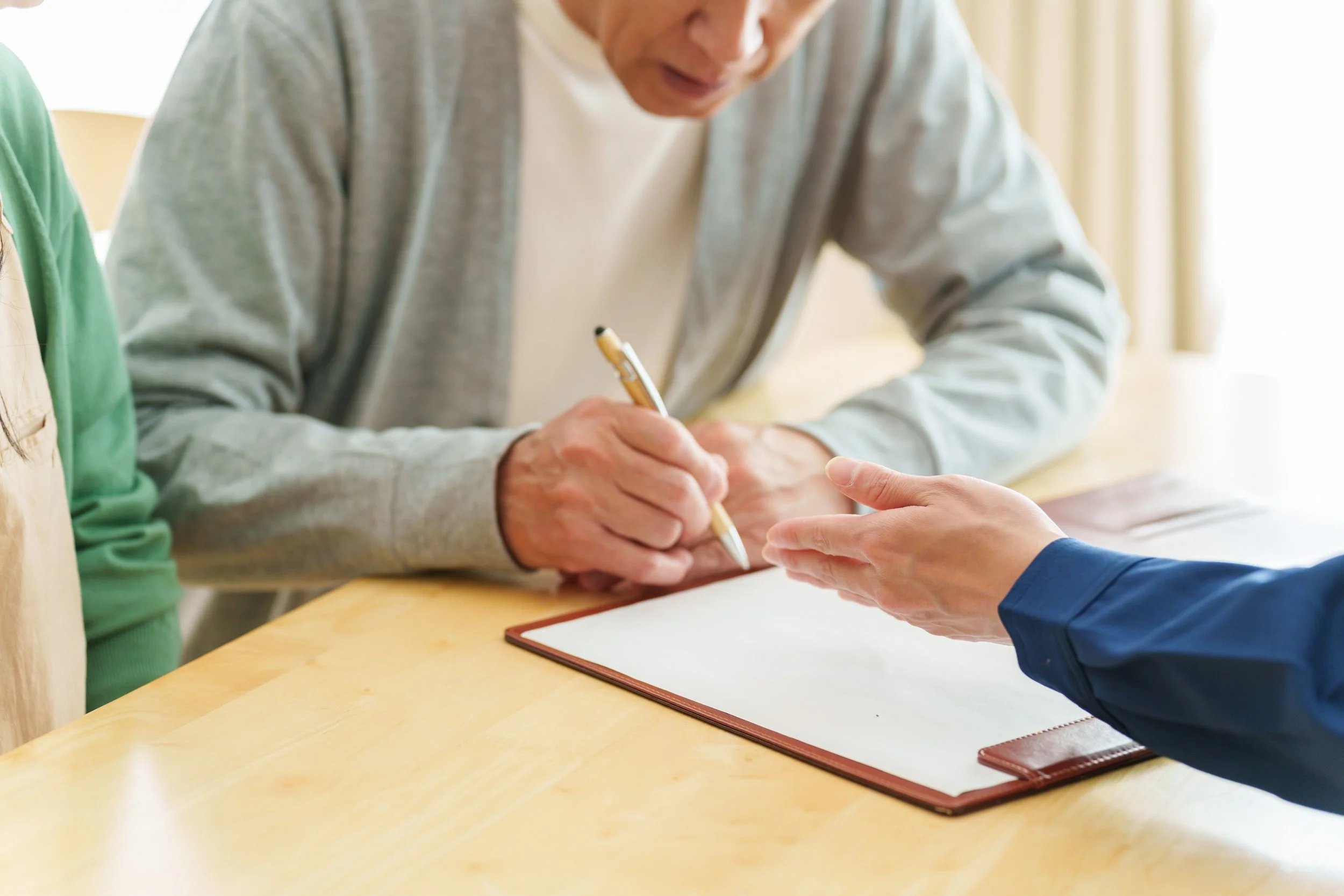 An elderly man signing his Will with his solicitor present to witness and advise
