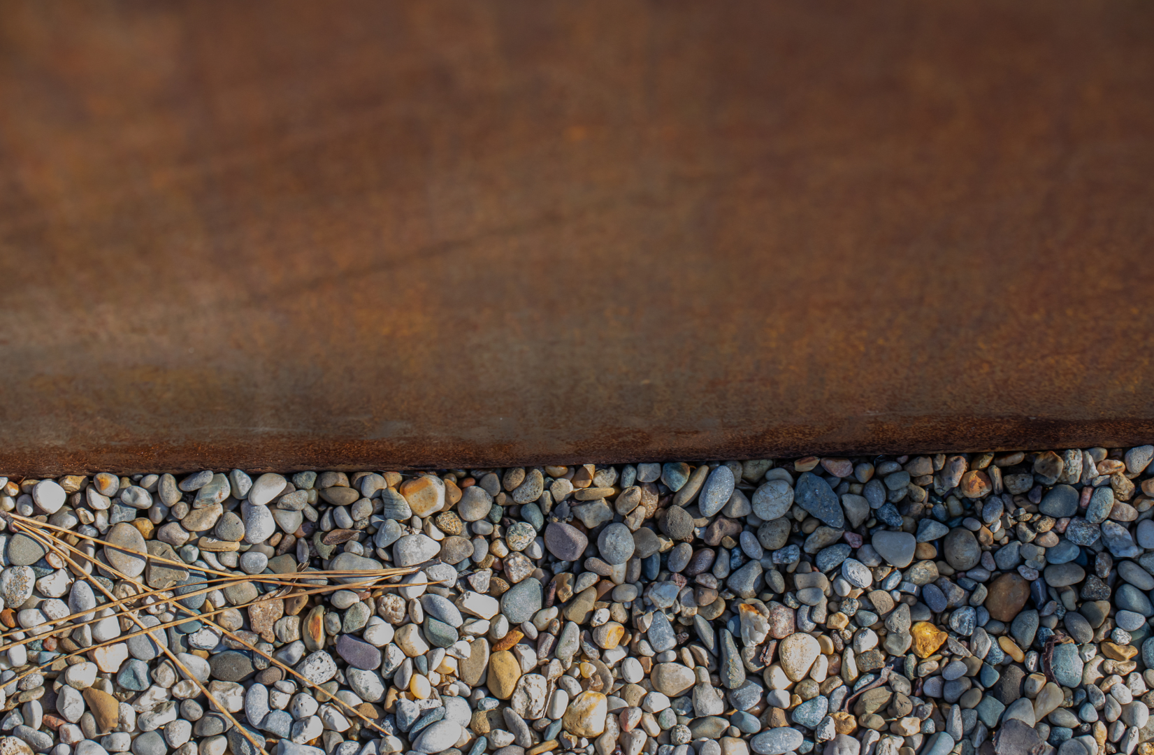 Multicolored pea gravel complements the rusted steel beds. 
