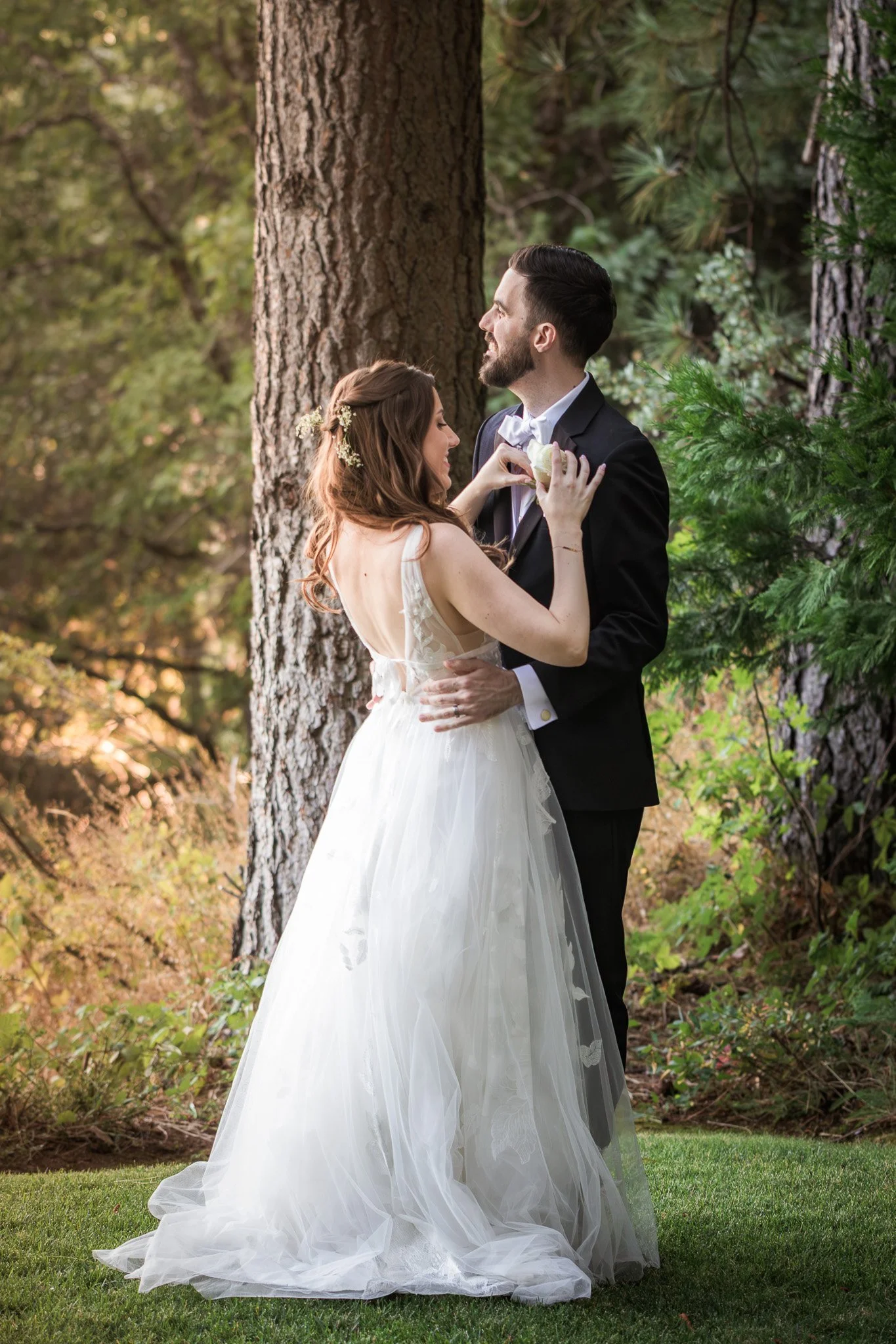 A bride and groom share a romantic moment in a forest setting.