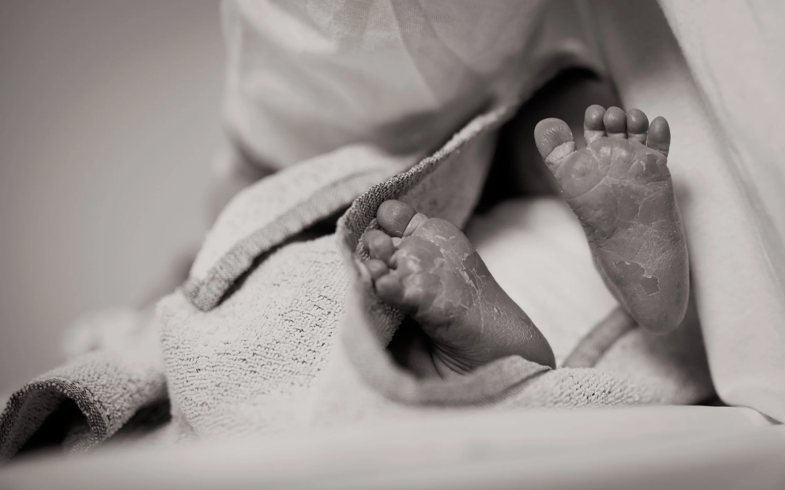  Newborn baby feet wrapped in a blanket. The mother experienced birth trauma and gets birth trauma treatment in Miami to cope with birth trauma PTSD. She works with an online therapist in Florida at the Heard Counseling 
