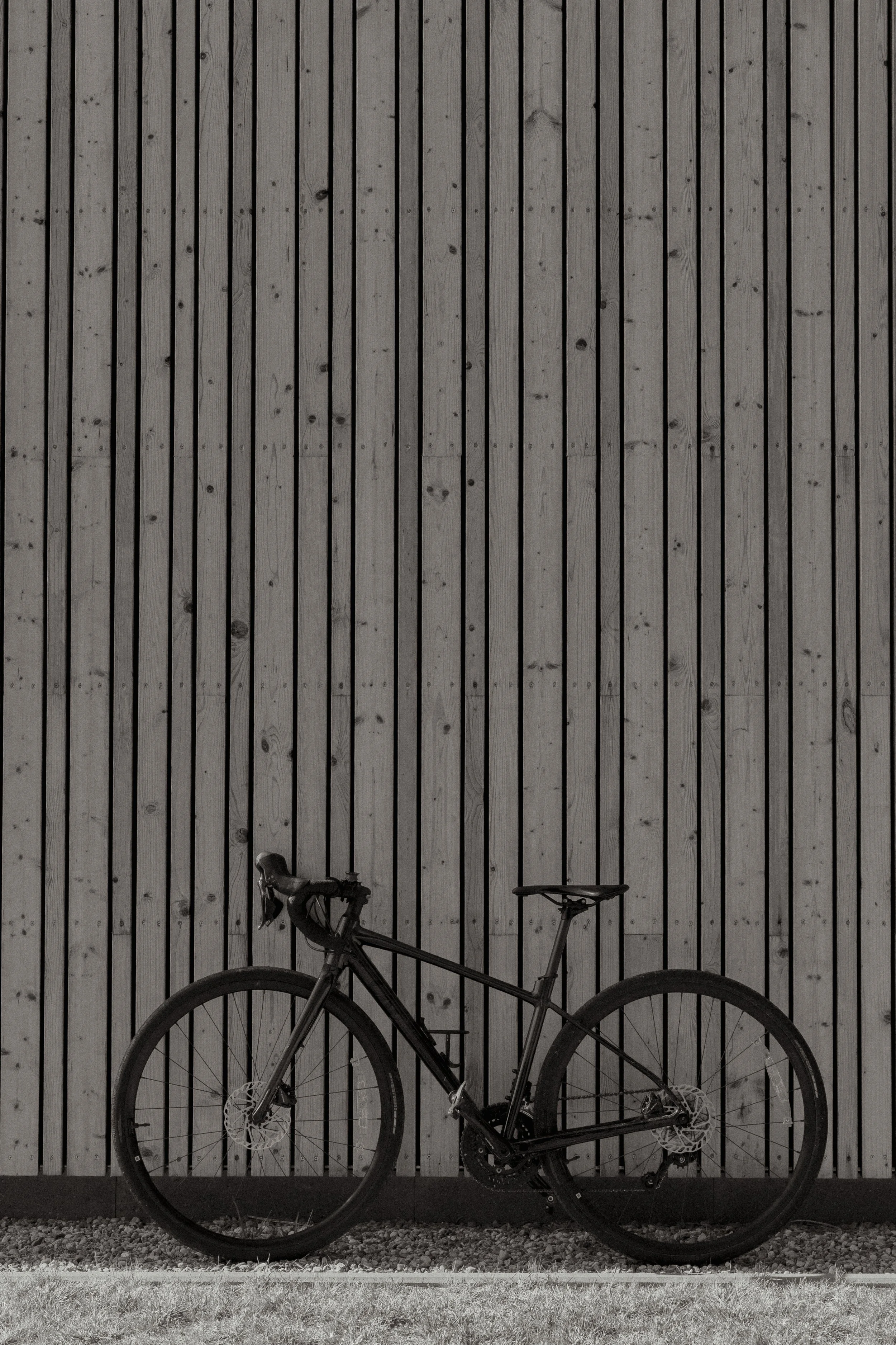Bicycle leaning against a wooden plank wall.