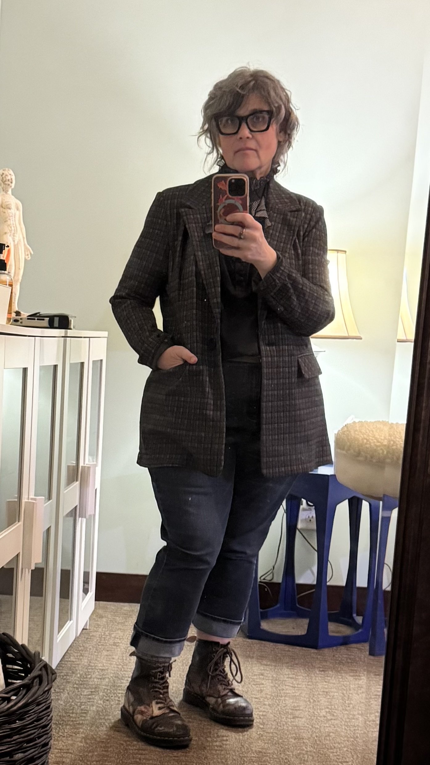 Krista McCain faces a full length mirror in her office, and stands next to a white acupuncture supplies cabinet.