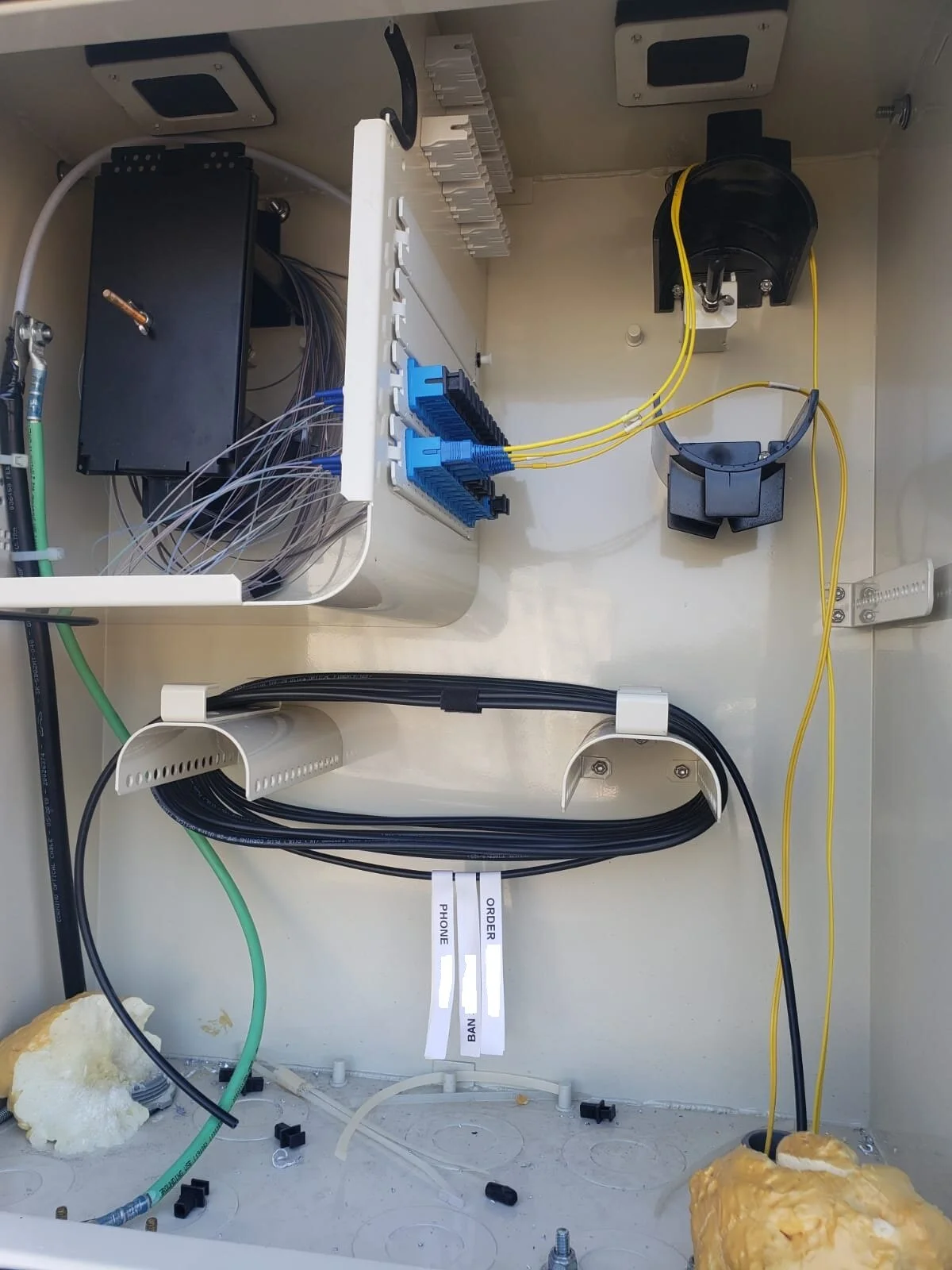 Inside of an electrical or networking cabinet with various cables, connectors, and equipment.