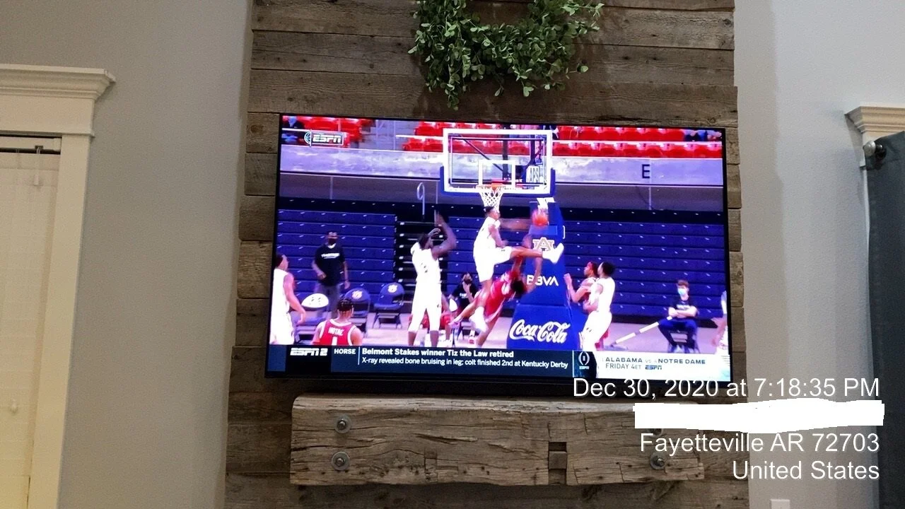 A basketball game on a TV screen showing players in white uniforms during a layup or dunk attempt in an indoor gym, with some players wearing masks, and ESPN logos visible.
