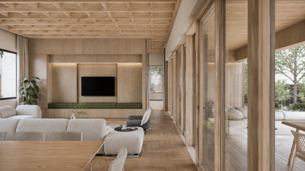 Living area at Estuary House in Mount Martha, featuring timber-framed glazing, a coffered timber ceiling, integrated joinery and a direct connection to the covered outdoor terrace.