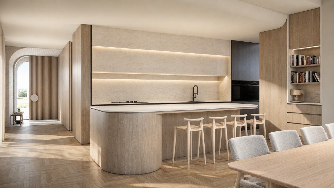 Kitchen and dining area at Estuary House in Mount Martha, featuring curved timber joinery, a stone island bench, integrated appliances and a framed view to the entry.