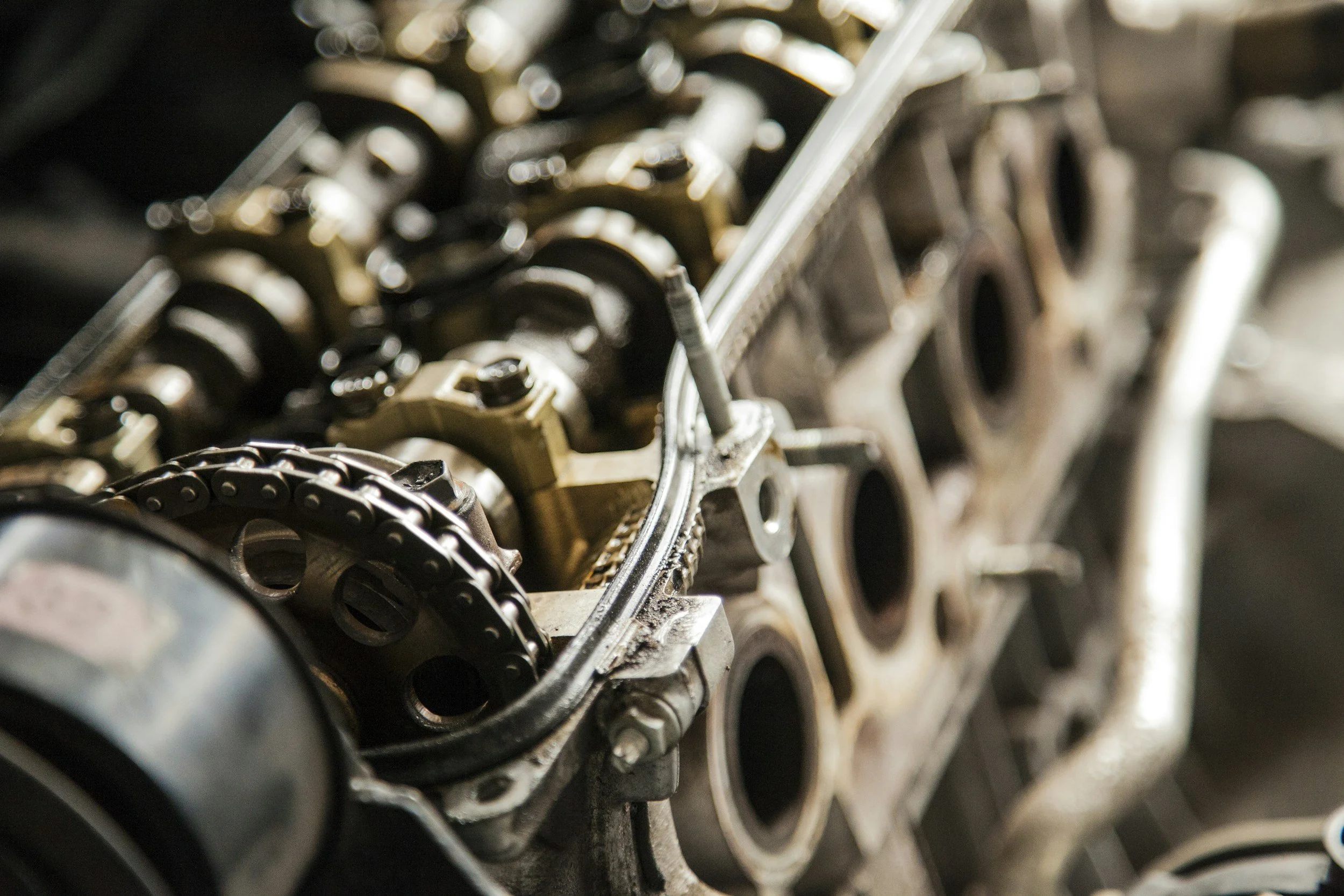 Close-up of an engine block with visible cylinders and timing chain, parts of an automotive engine under maintenance or repair.