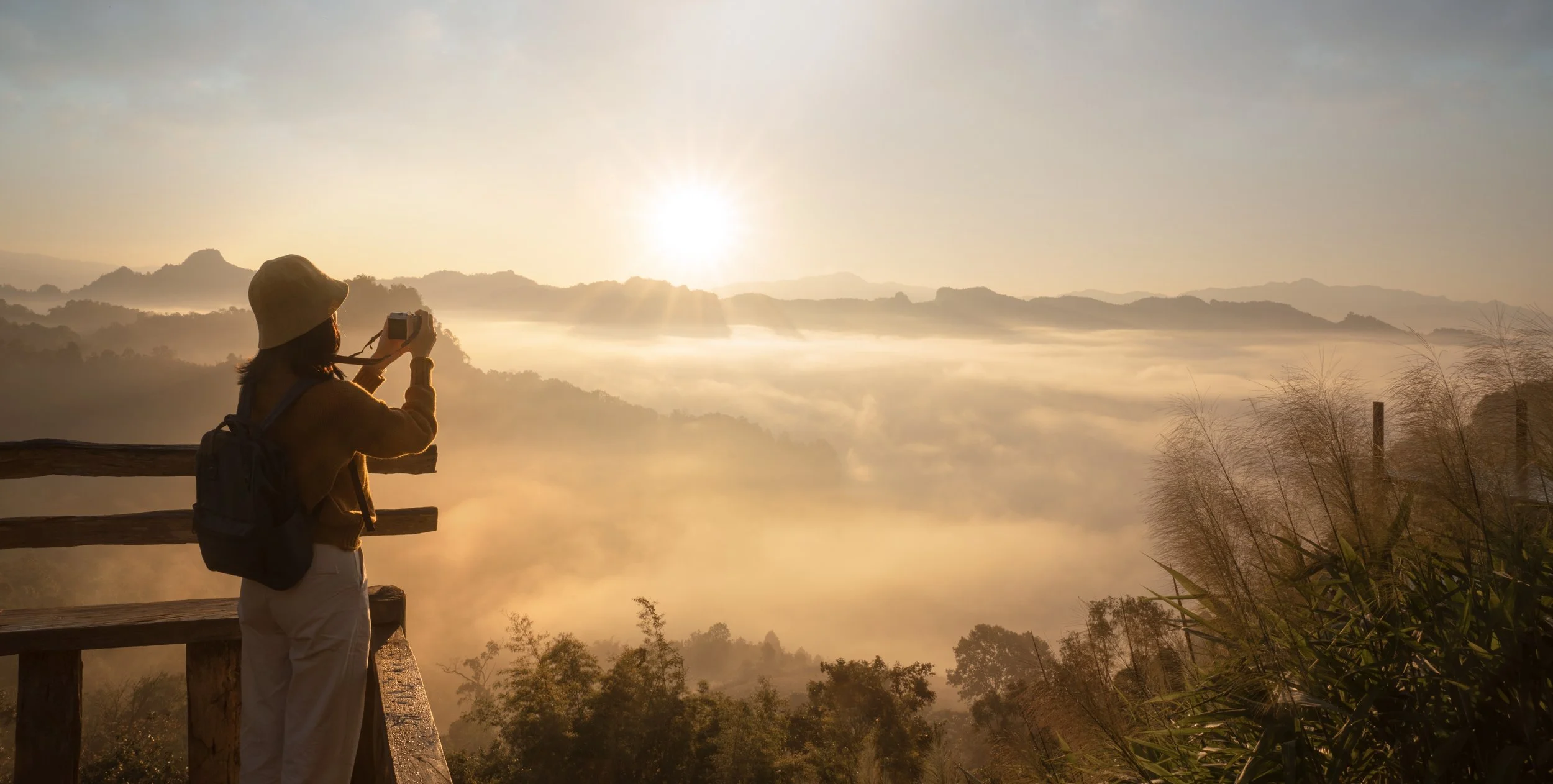 A traveller pausing to photograph the sunrise over a misty landscape — representing the patience and long view the three bucket retirement strategy is built on