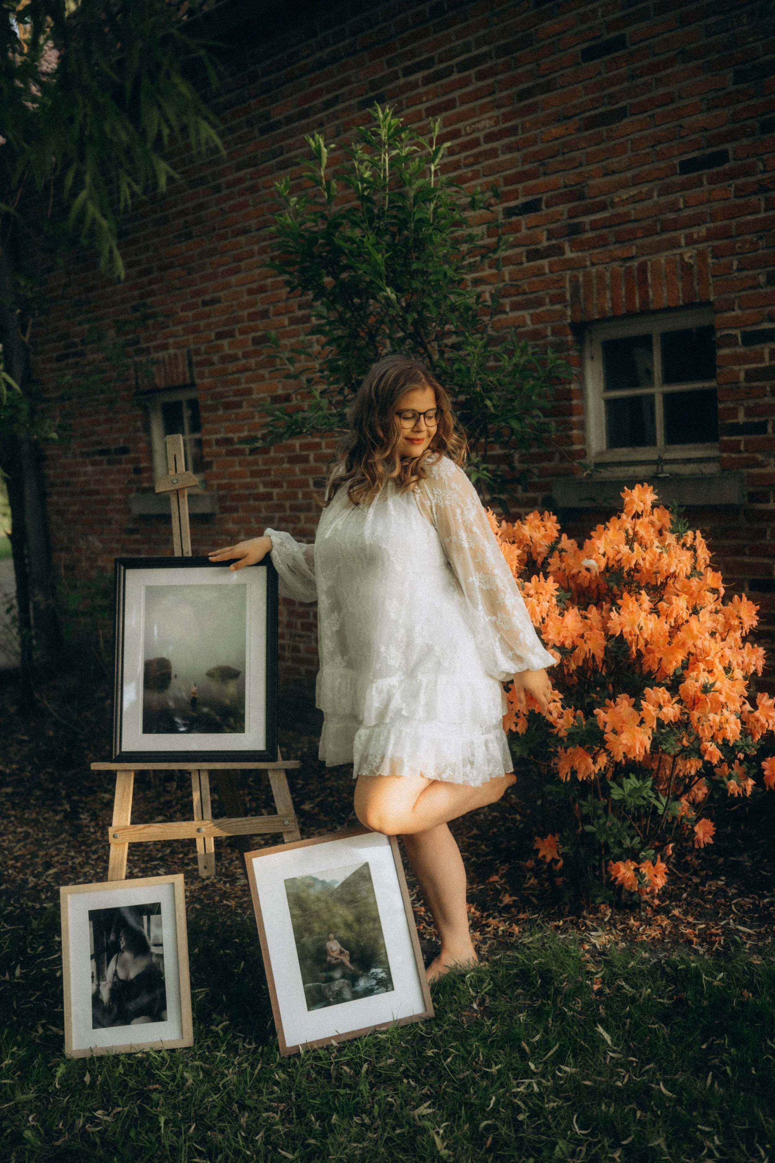 Vrouw bij schildersezel met fine art foto's in kader