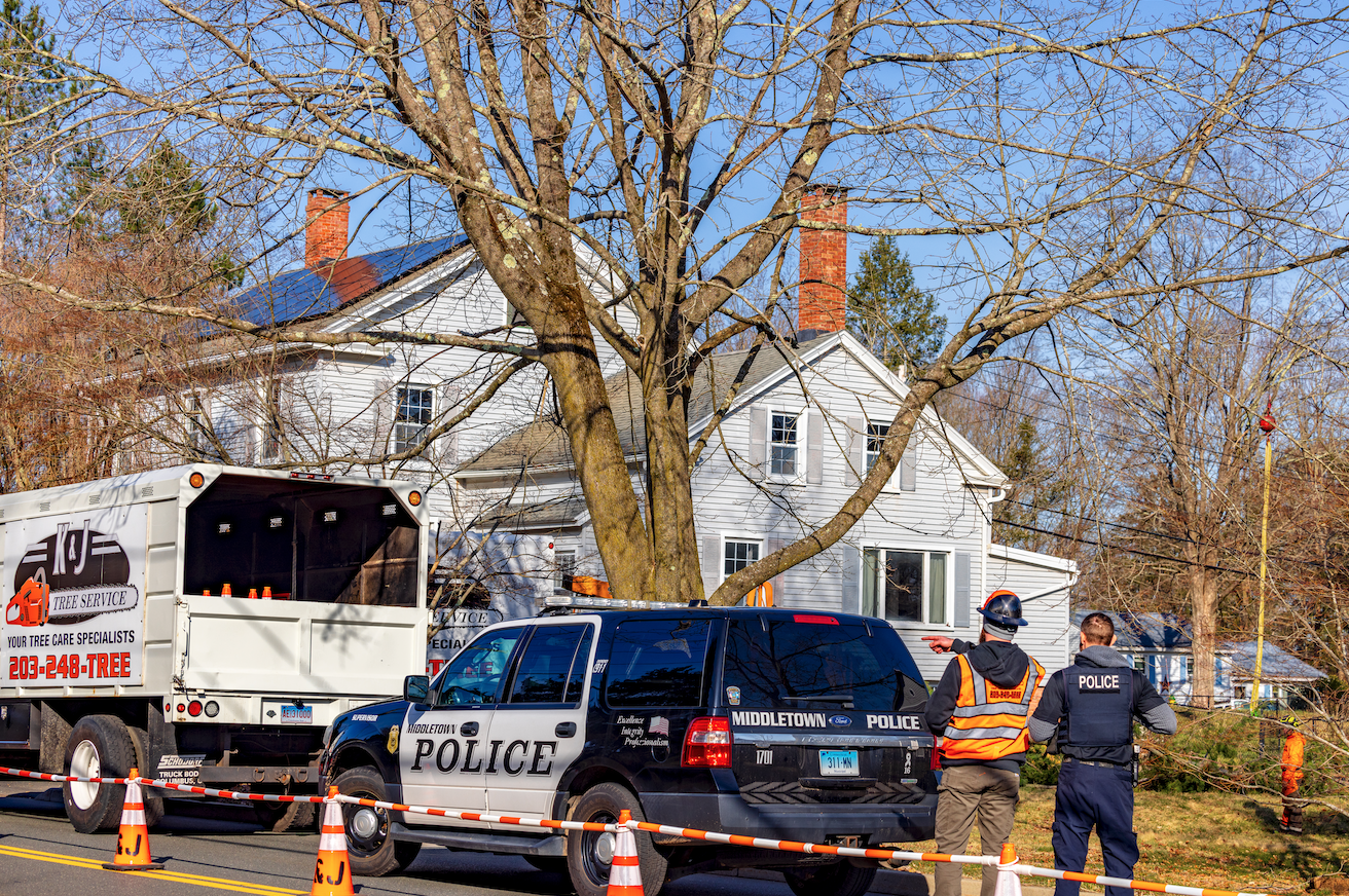 KJ Tree Service crew member speaking to Middletown police officer at job site.