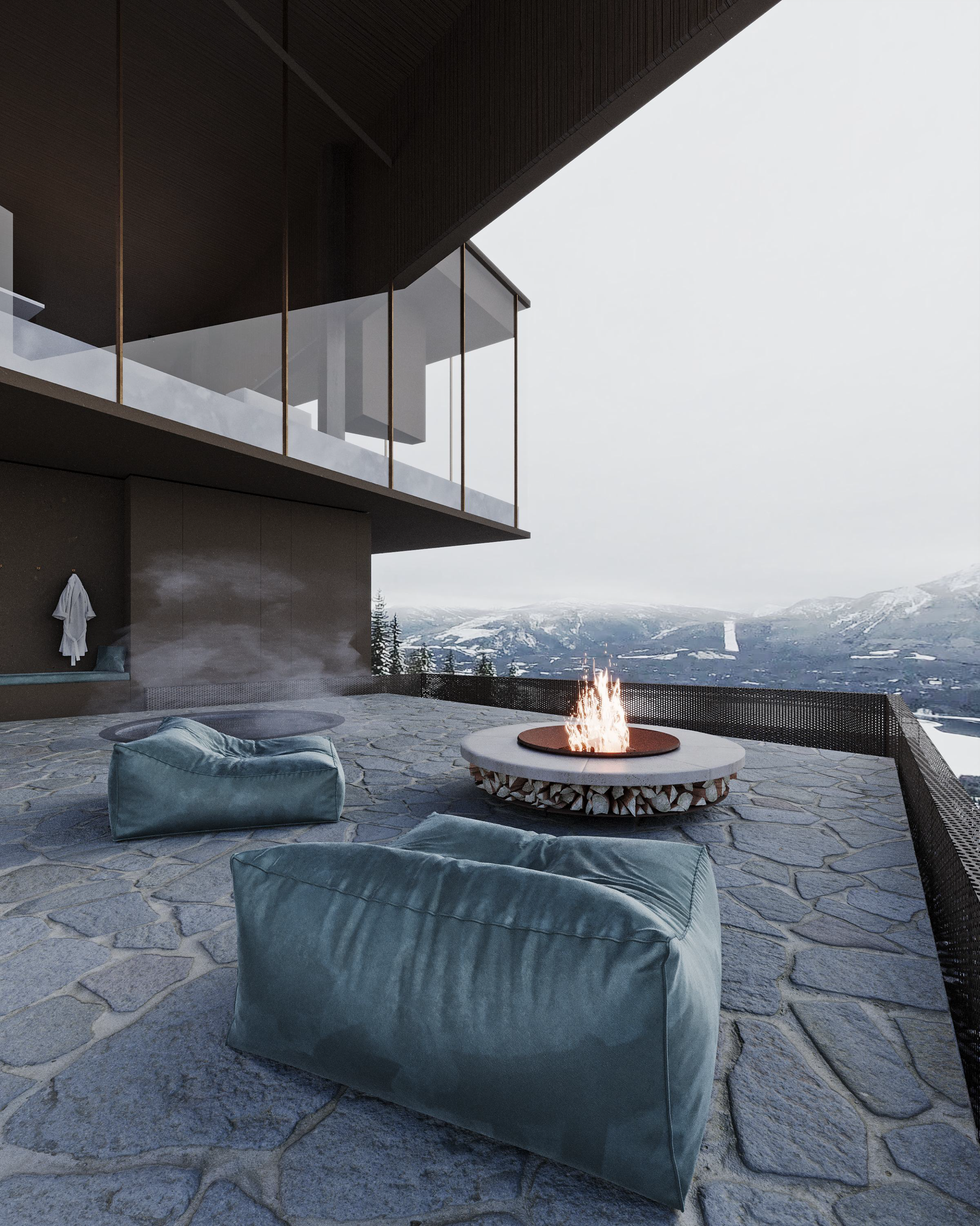 Modern outdoor terrace with stone flooring, two blue bean bag chairs, a fire pit, and mountain views in the background.