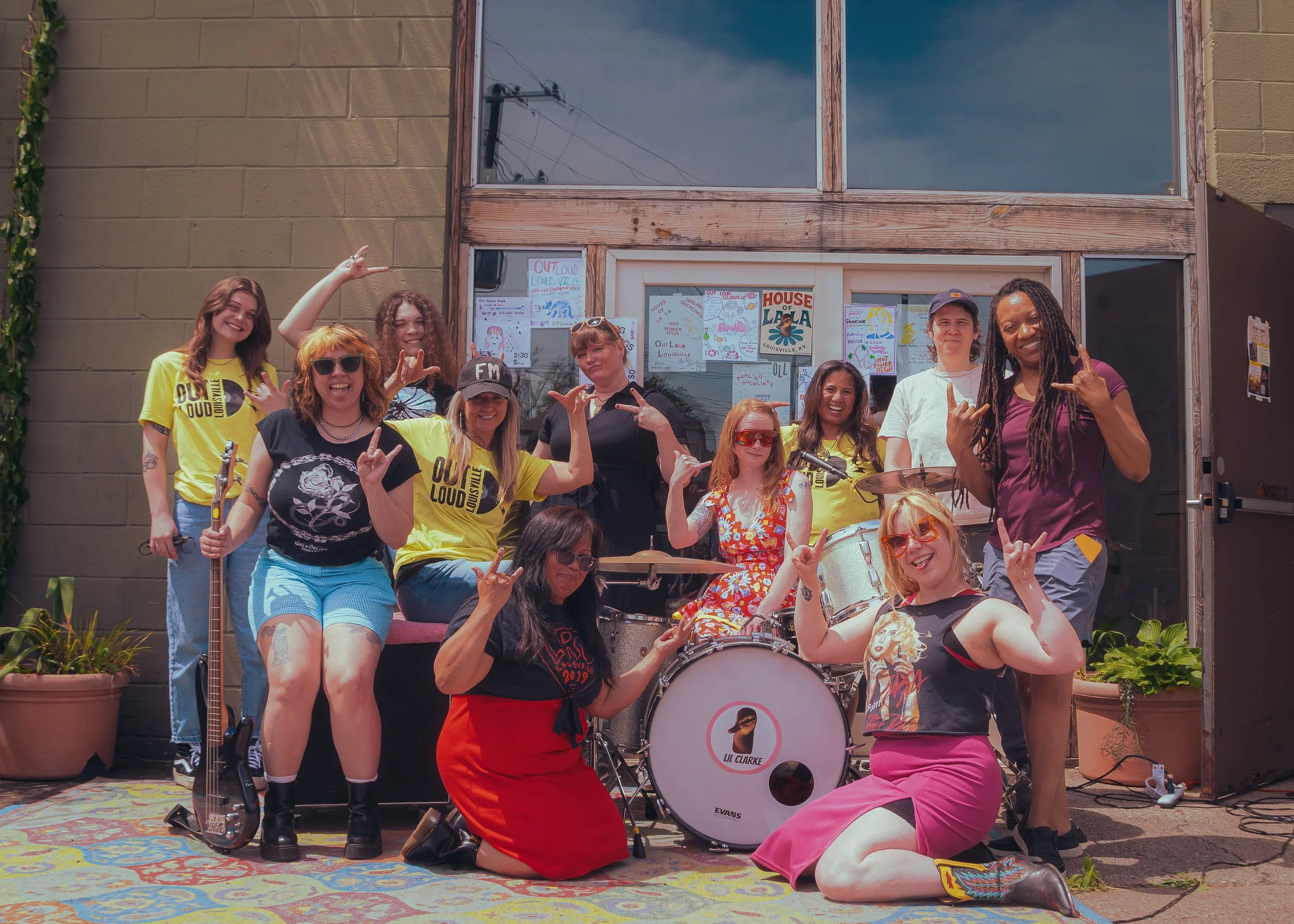 The photo shows a diverse group of femme adults holding instruments and posing for a photo.