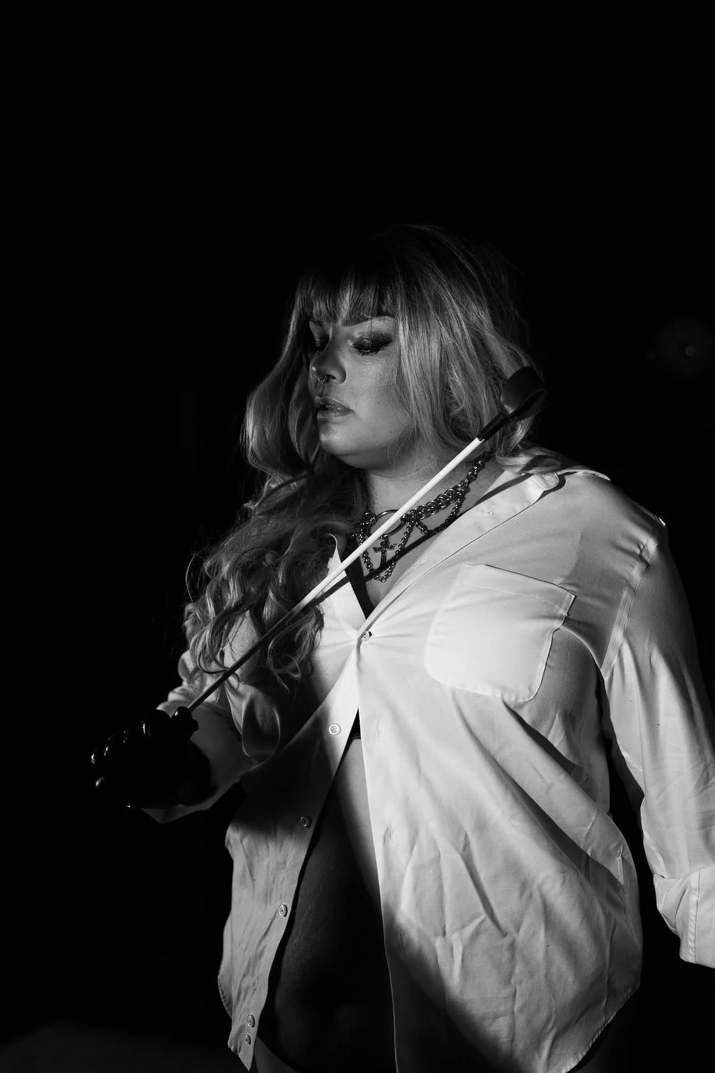 Madame in black and white, holding a riding crop