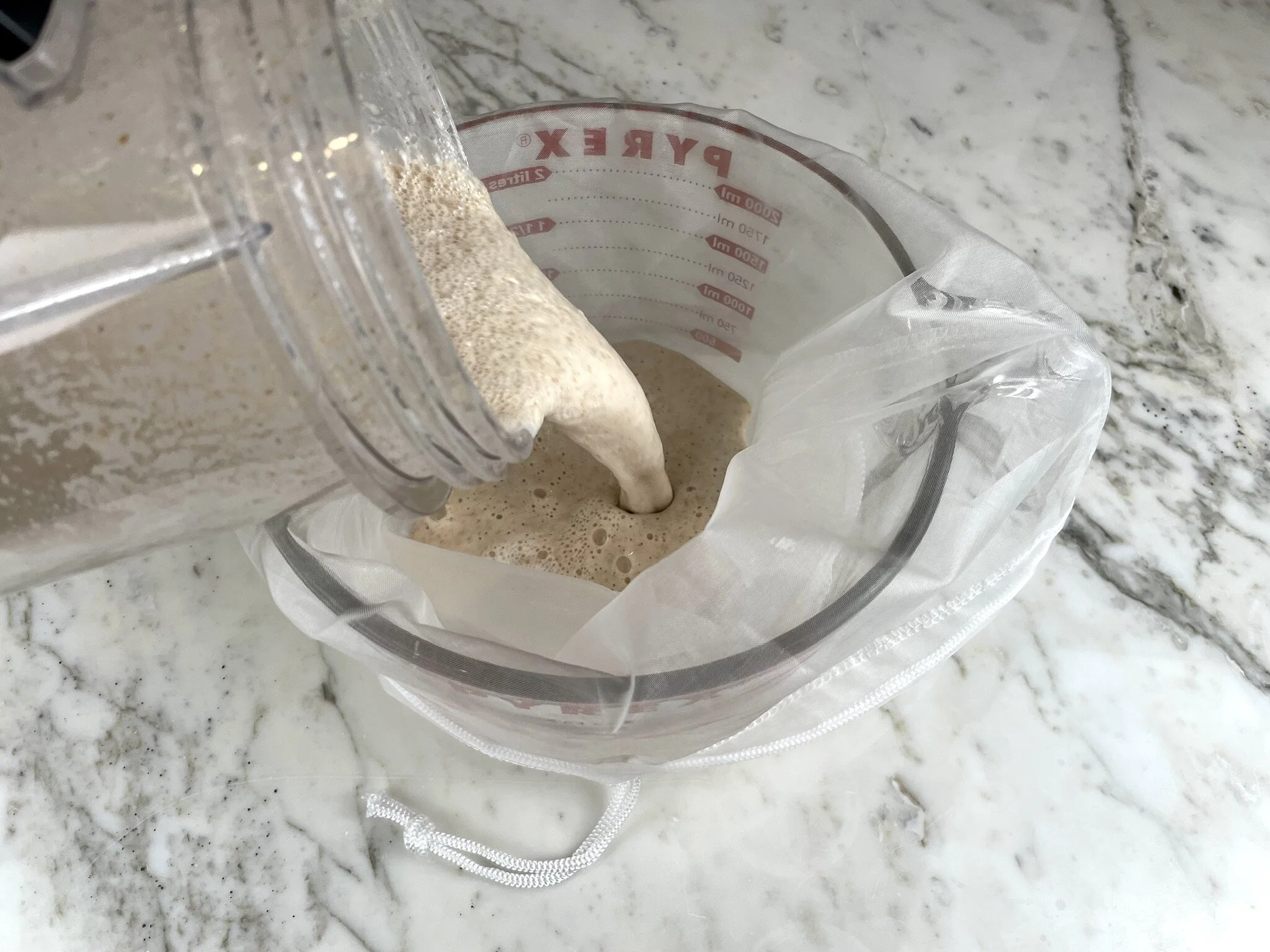 Pour nut milk thru bag.