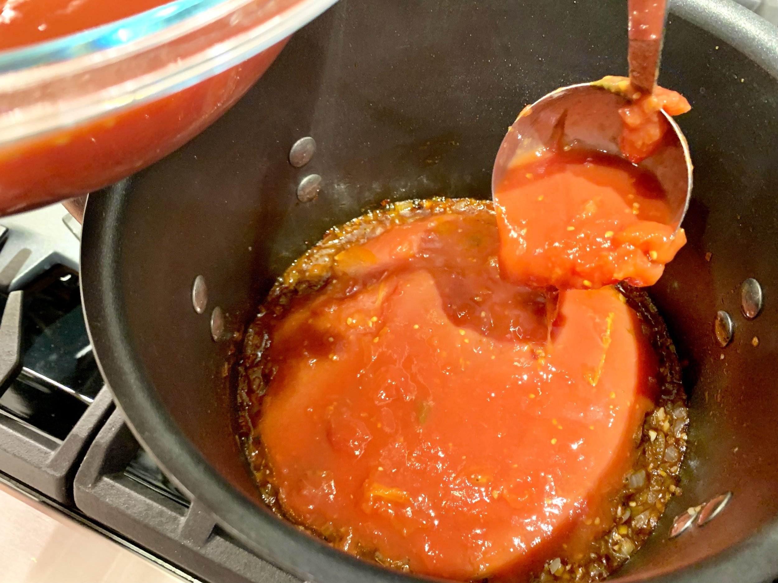 Ladle tomatoes into pot.