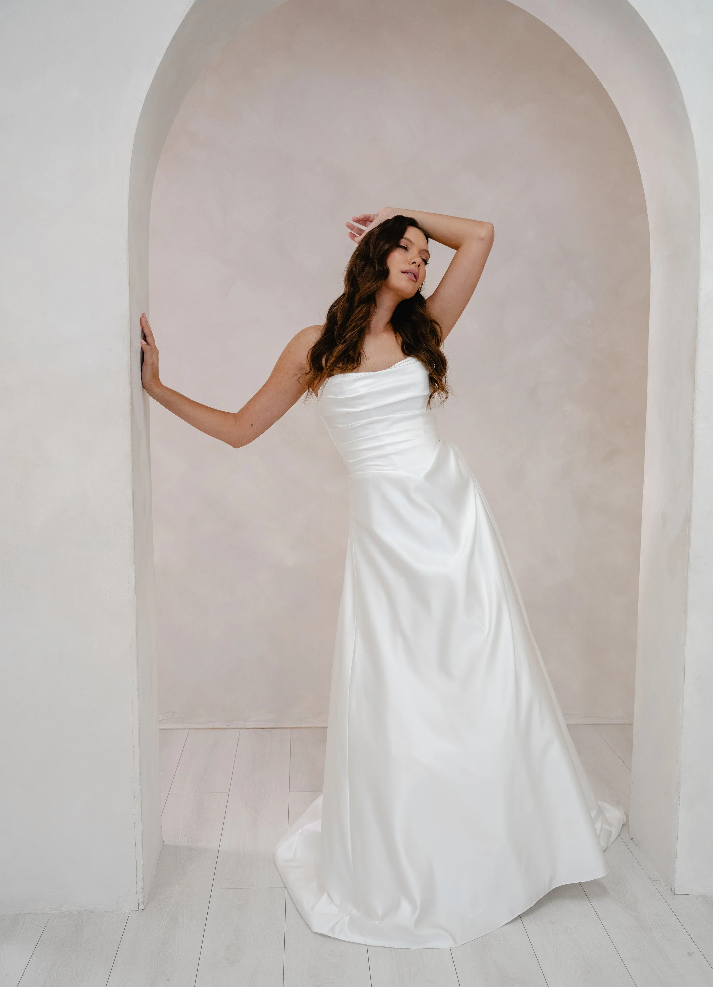 Strapless bridal gown on woman standing in doorway with arms in the air