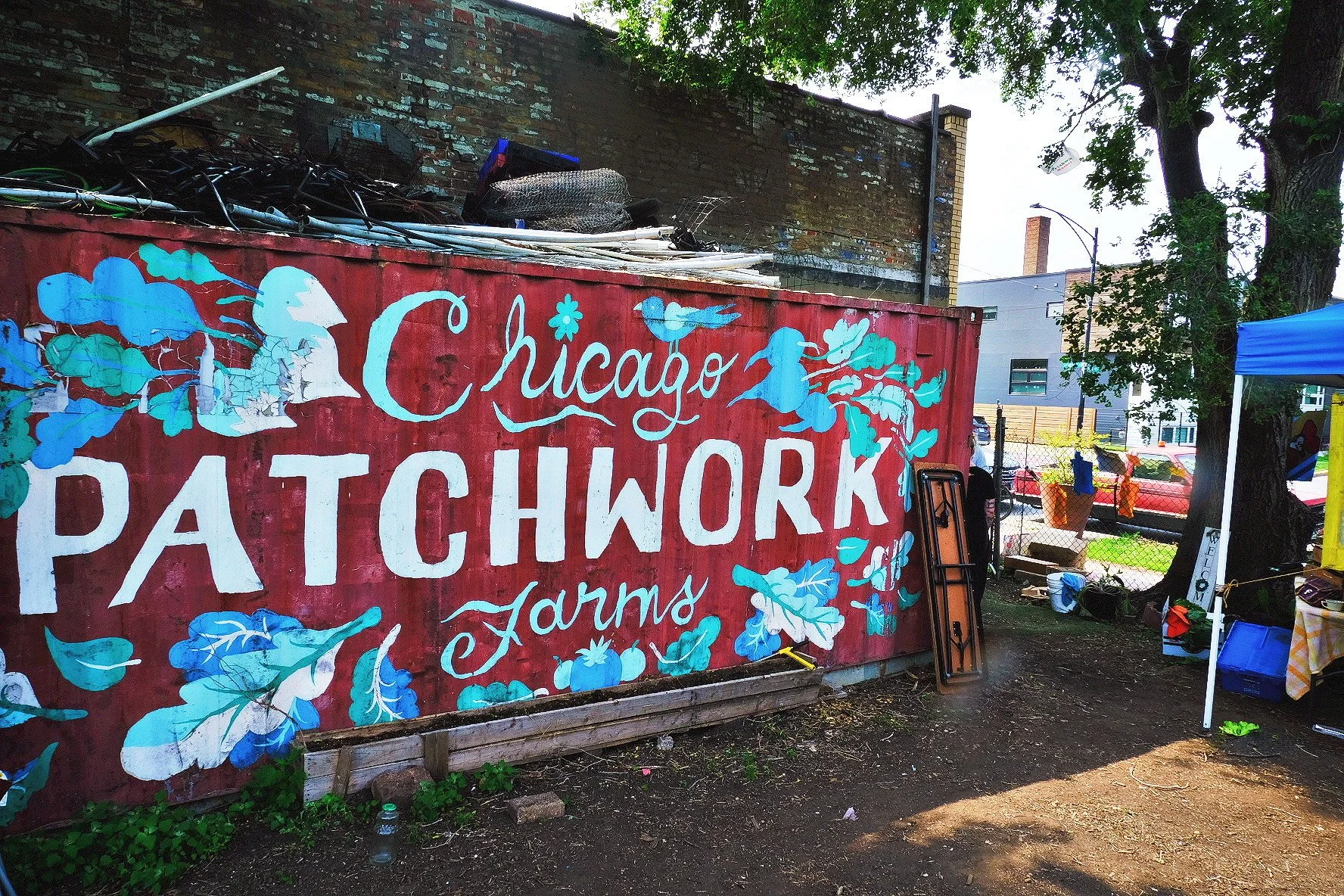 red shipping container with painted green and blue leaves and text that reads Chicago Patchwork Farms