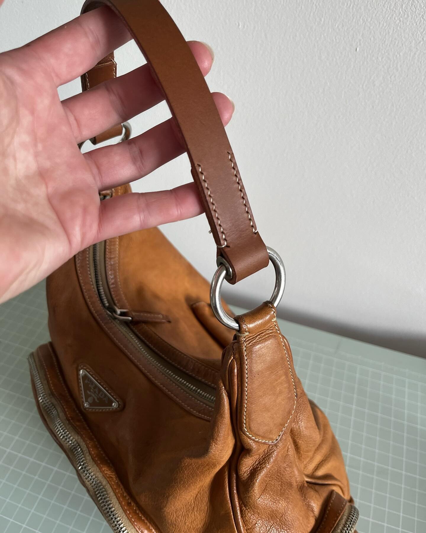 This @prada bag came to me as the original strap had snapped and disintegrated.  The bag had been well worn over the years.

I created a new handle from a brown vegetable tanned leather that I had.  This is the leather which is around 3 - 4mm thick. 