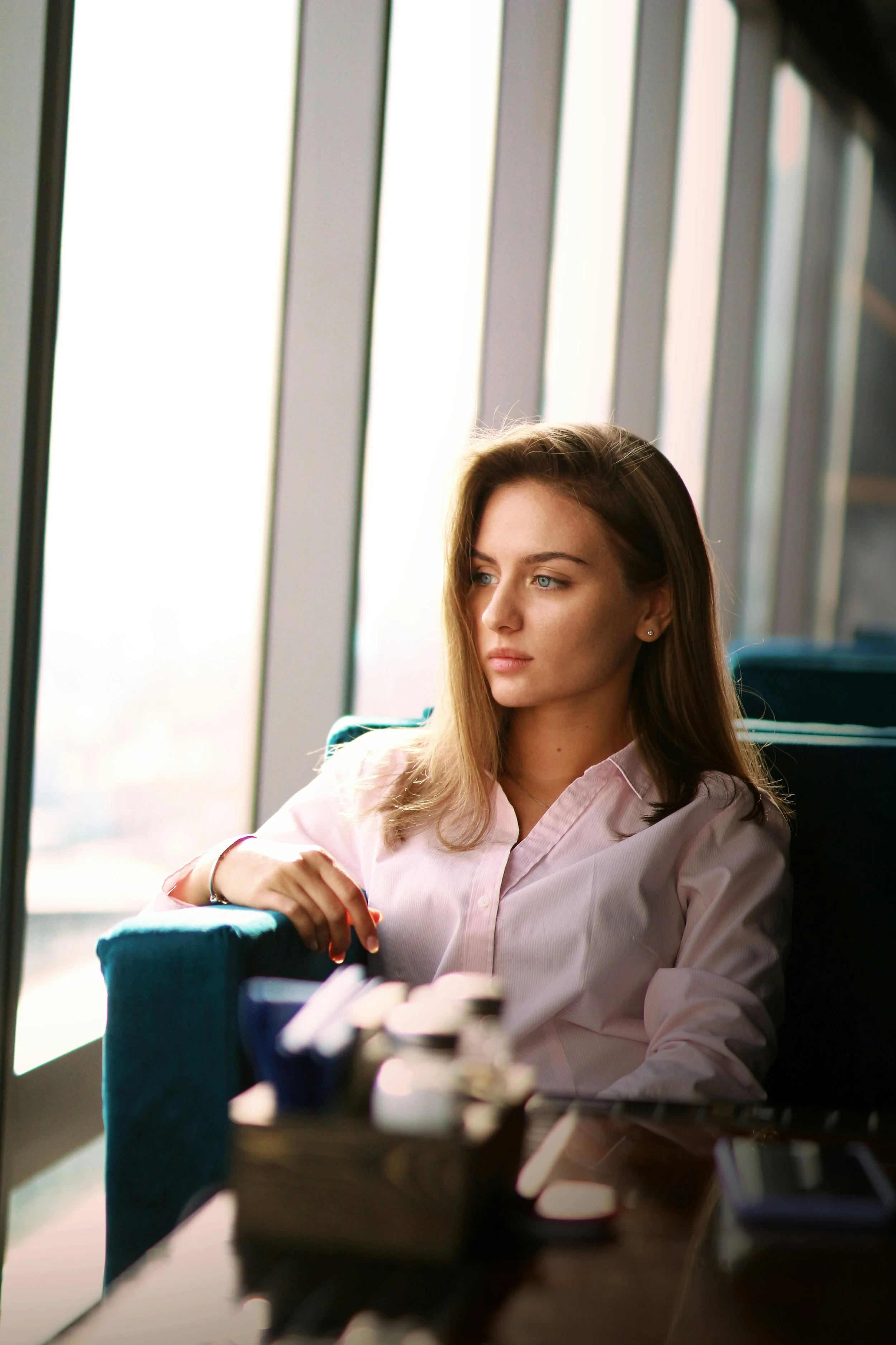Professional woman sitting thoughtfully by a window, reflecting quietly and experiencing mental overload and overthinking