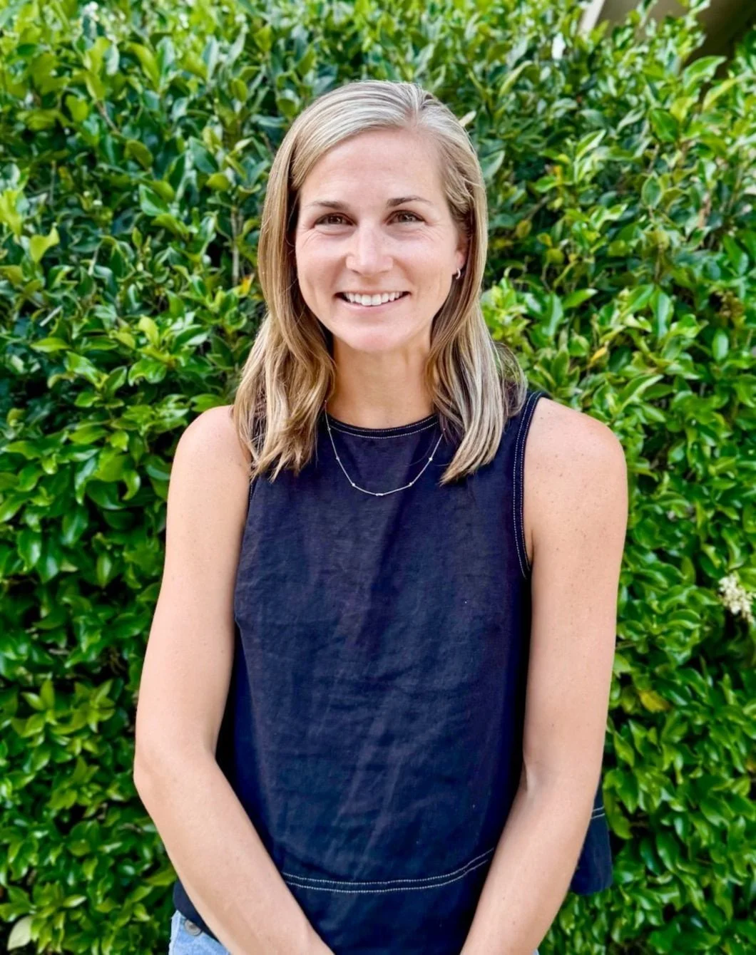 Kimberly Etherton in front of greenery smiling in a navy shirt