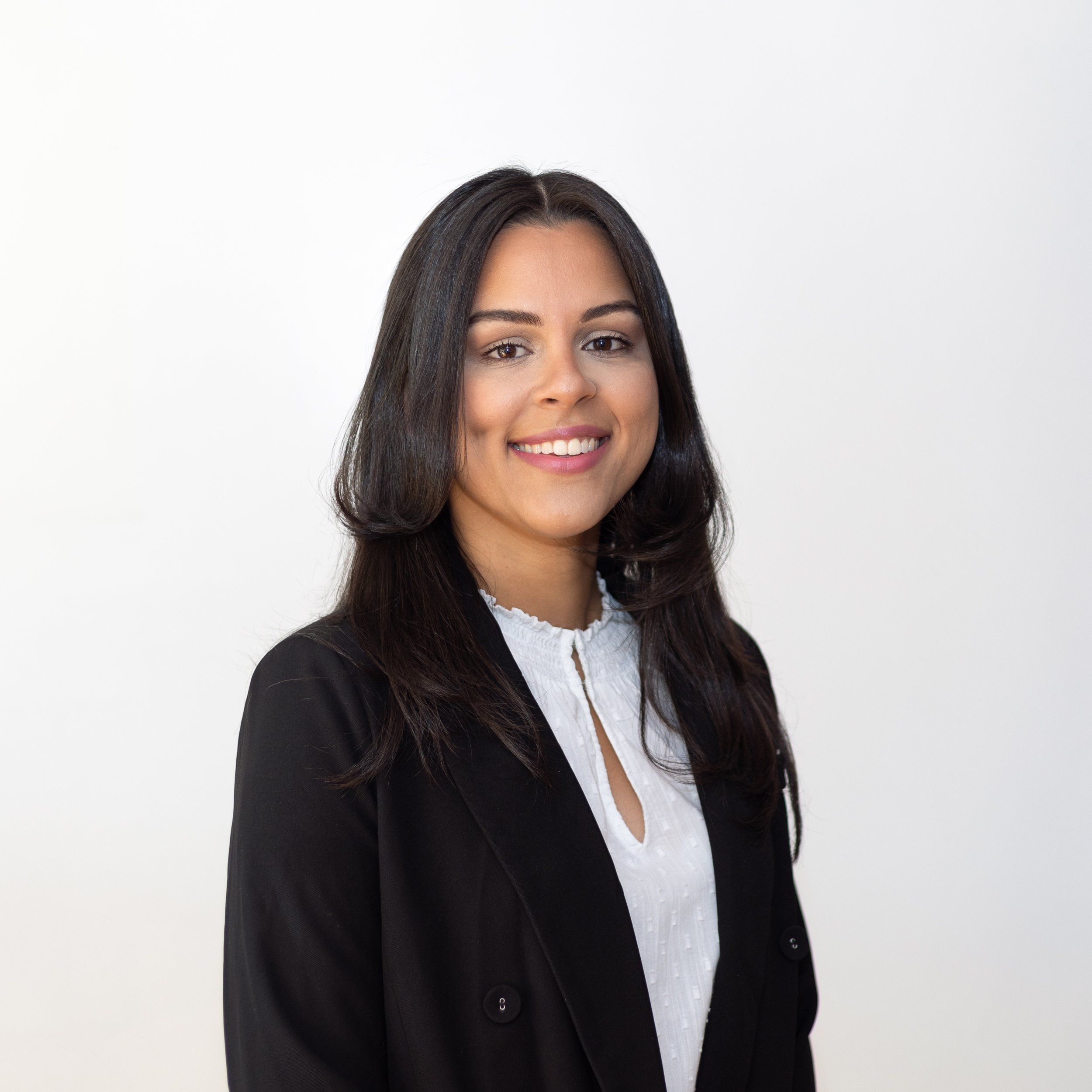 Smiling woman in business attire, black blazer, white shirt, against a white background.