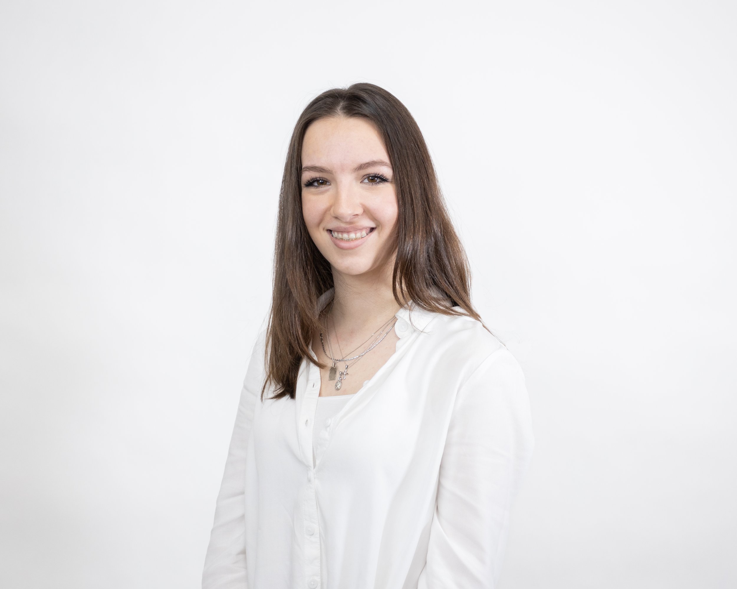 Smiling woman in white shirt against plain background.