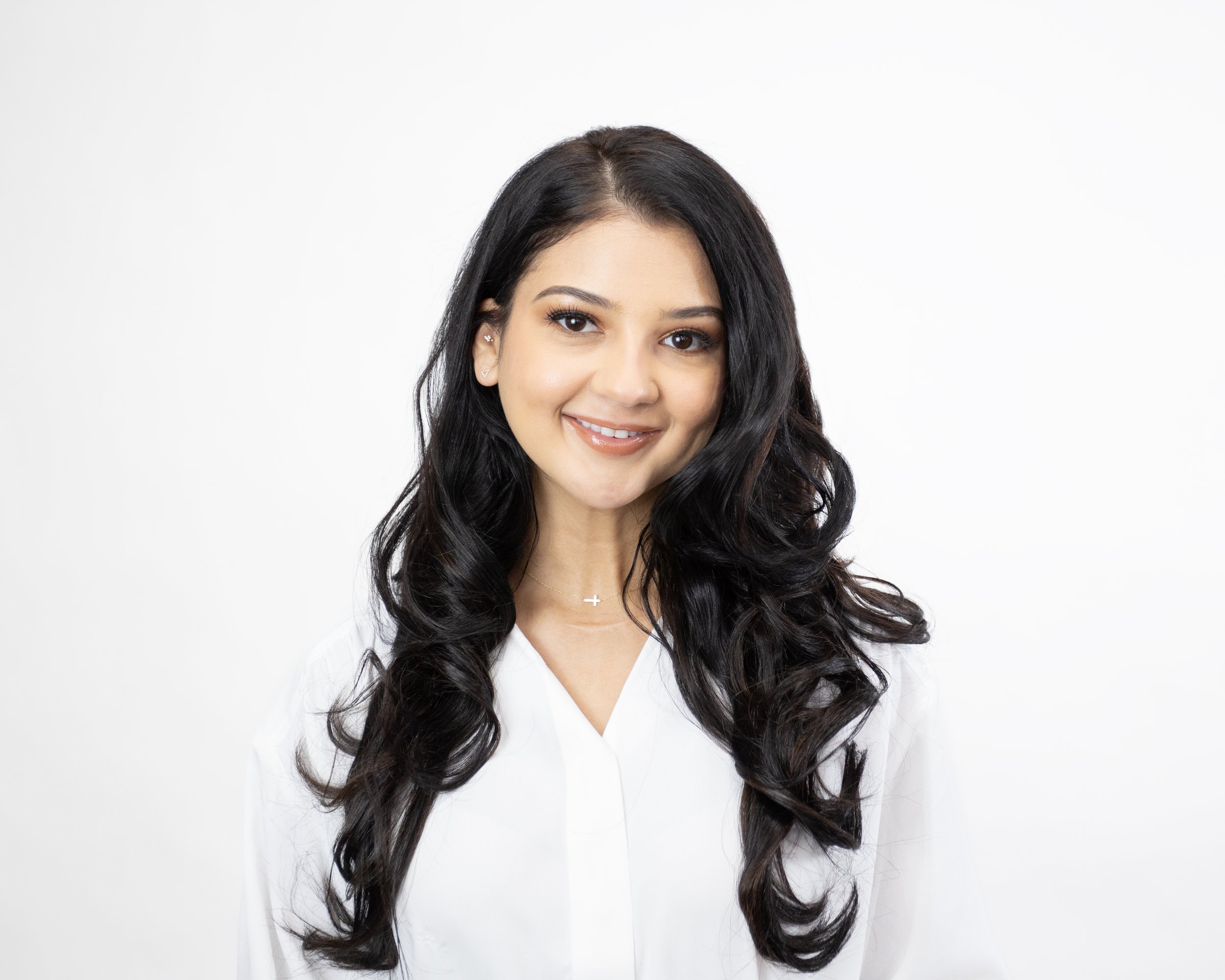 Smiling woman with long dark hair, wearing a white shirt.
