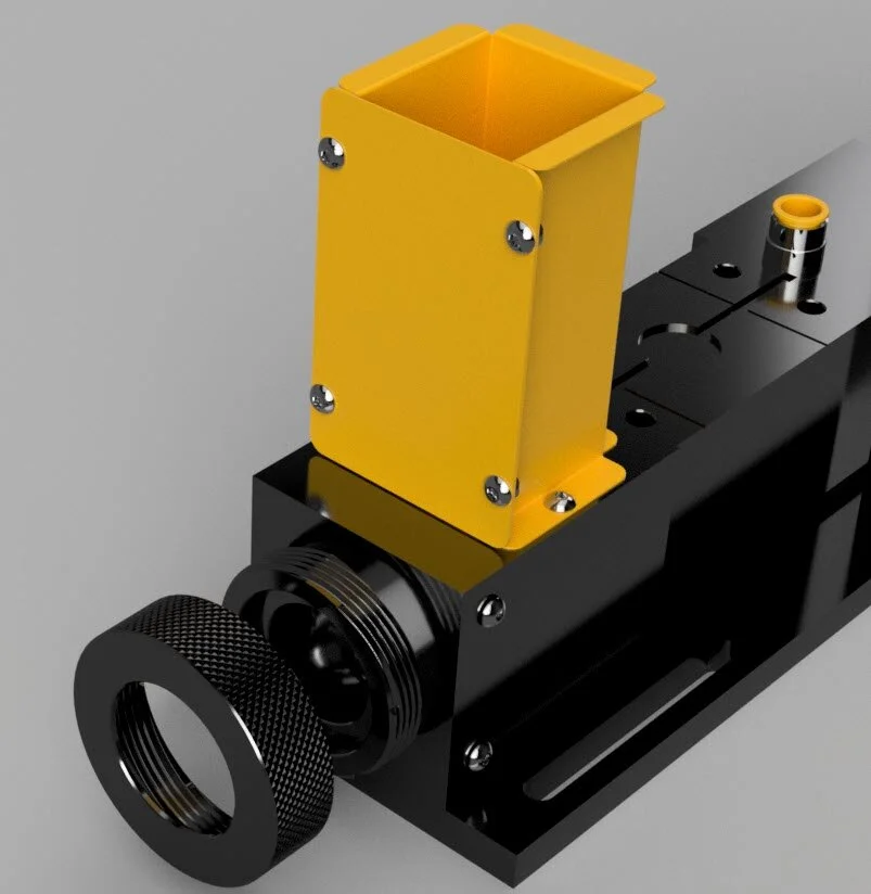 Close-up of a mechanical assembly featuring a black base, a yellow rectangular component attached with screws, and a knurled black circular knob on the side.