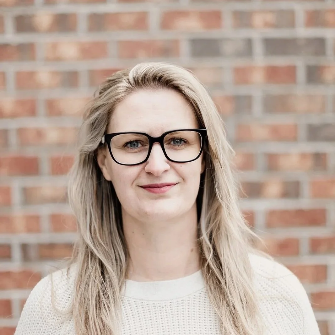 Lady standing in front of brick wall.