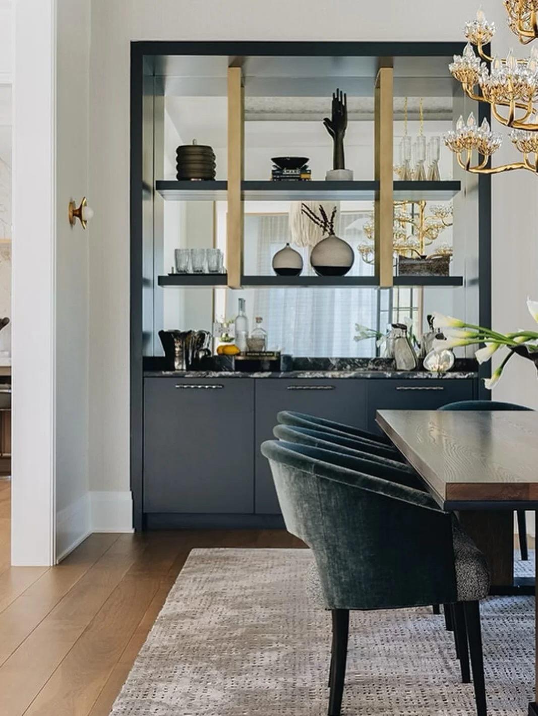 A dining room with a built-in bar&mdash;what more could you ask for when entertaining guests?
⠀⠀⠀⠀⠀⠀⠀⠀⠀
This custom showpiece is painted in a rich, dark hue to create a striking contrast within the room. The mirrored backsplash adds depth and a touch