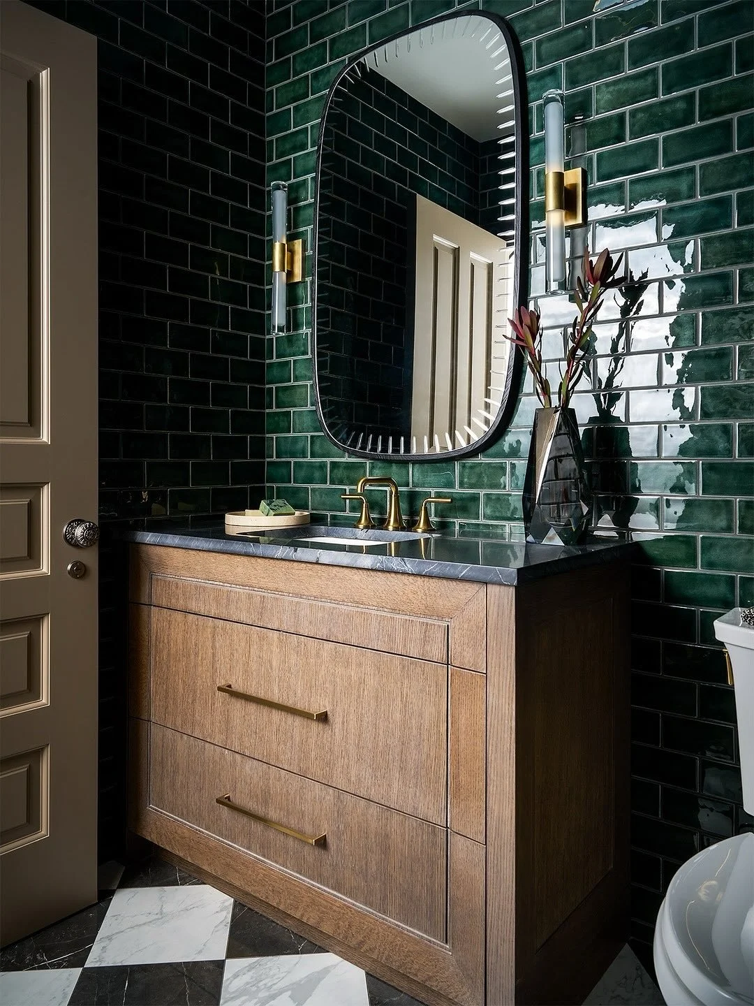 A bold take on the classic bath.
Part of our Hinsdale Historic Renovation project, this bathroom is wrapped entirely in rich green subway tile, making a statement from every angle. A black-and-white checkered floor adds timeless contrast, while brass