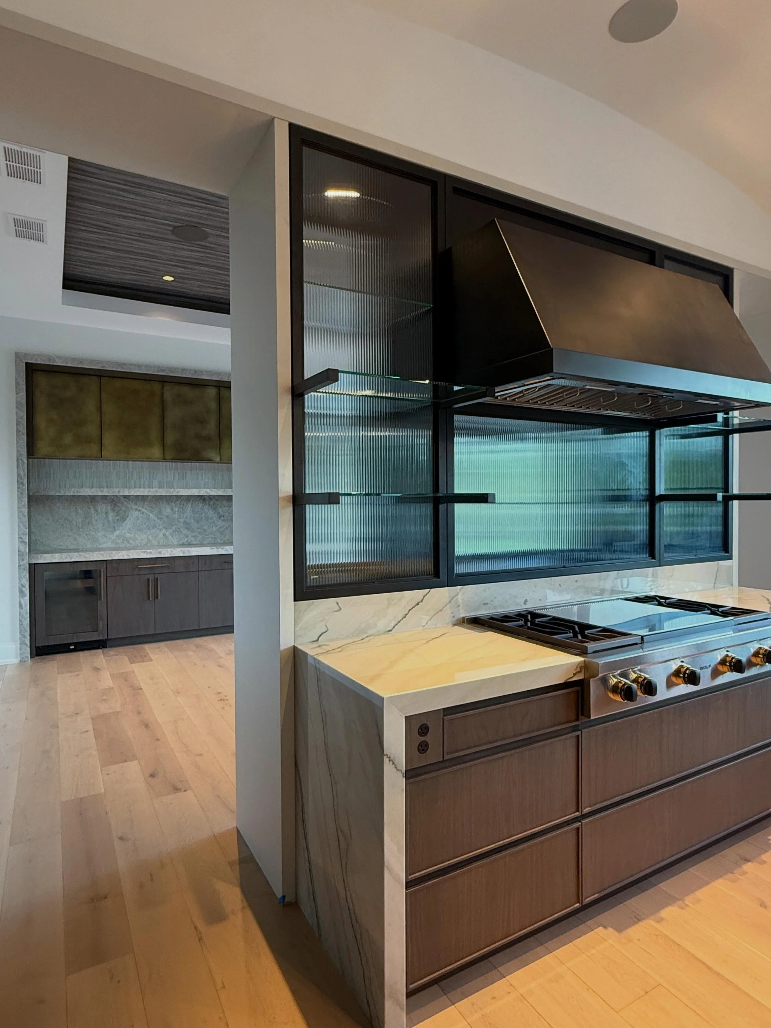 What appears simple is often anything but.

This architectural connection between the kitchen and dining room required extensive collaboration between cabinetry, metalwork, stone fabrication, electrical, and installation teams from the earliest stage