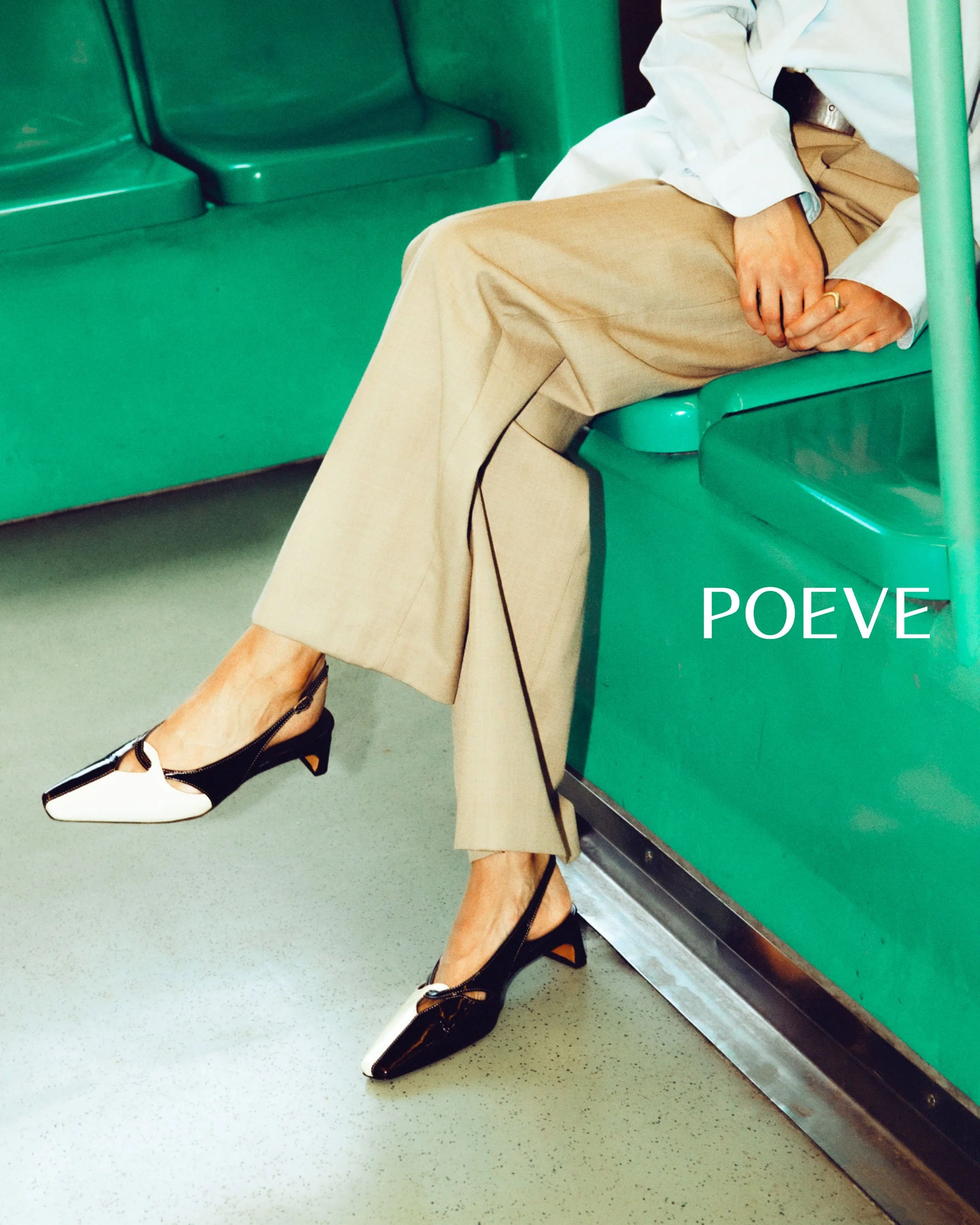A person sitting on a green bus seat, wearing beige pants and black and white high-heeled shoes. The person's hands are resting on their lap, with one hand visible. The background includes green parts of the bus interior. The text 'POEVE' is visible 
