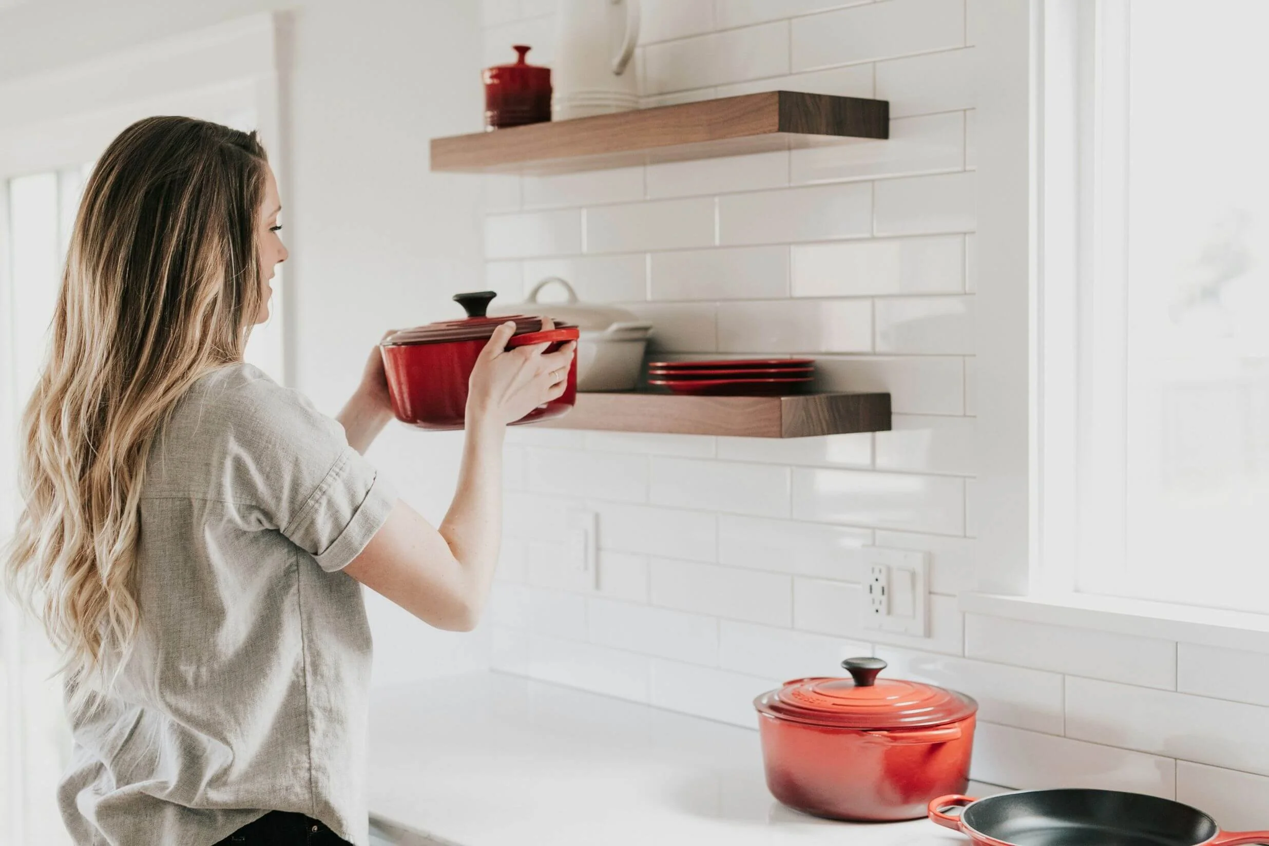 A woman organizing kitchen cabinets to prepare her home for holiday cooking and entertaining.