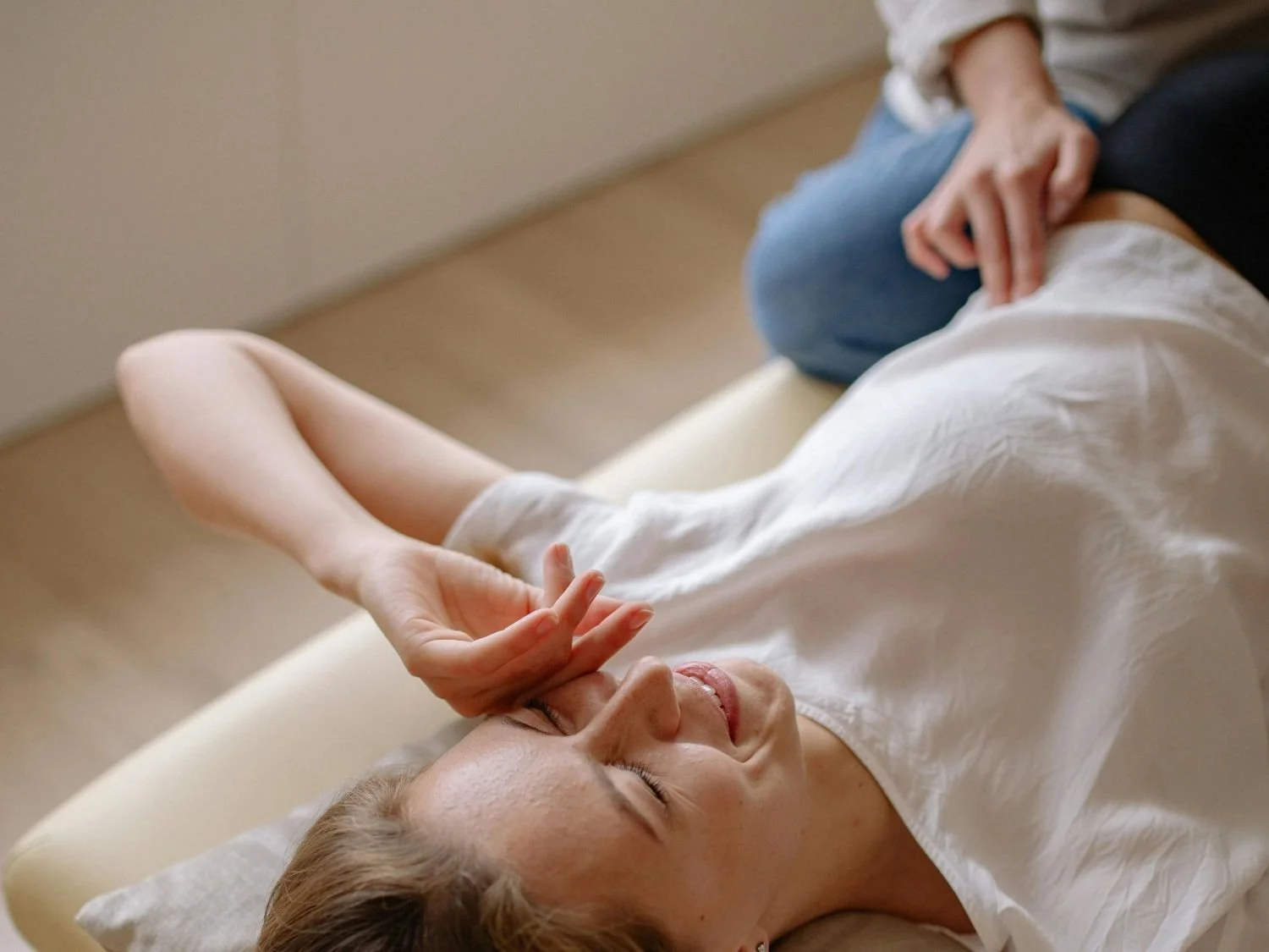 Woman smiling and feeling better while receiving a Specialized Craniosacral Therapy healing session.