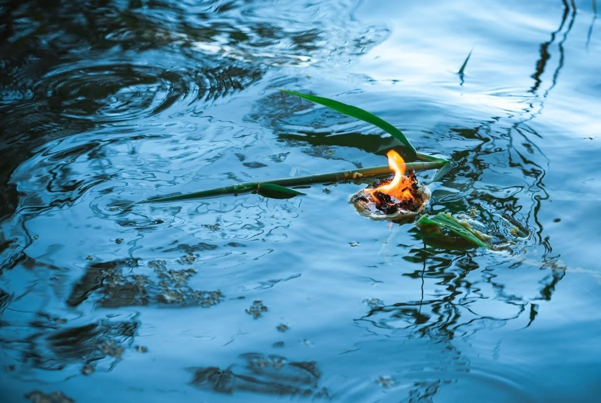 A ceremonial offering burning on the surface of rippling water.