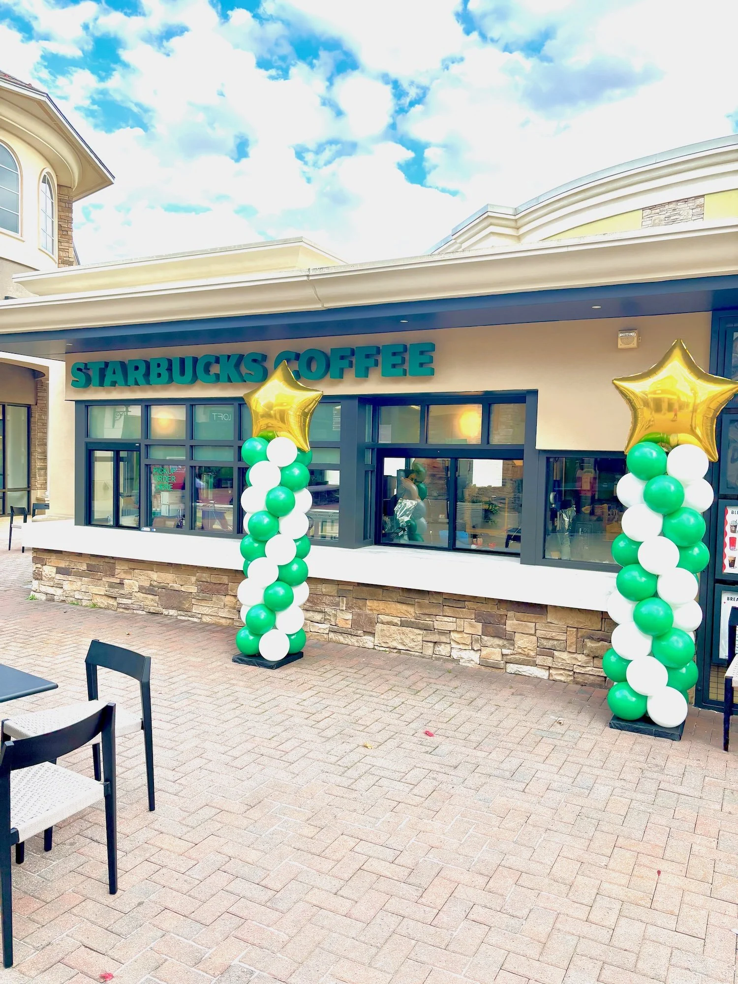 Corporate balloon columns in Starbucks brand colors of green, white, and gold for their grand opening event decor.
