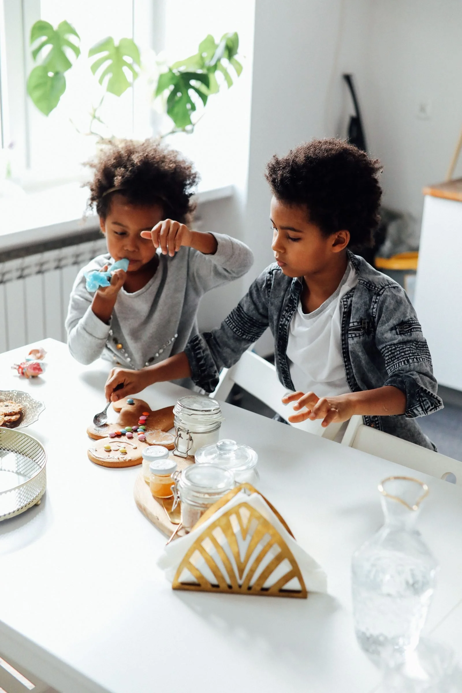Two children decorating cookies at a kitchen table